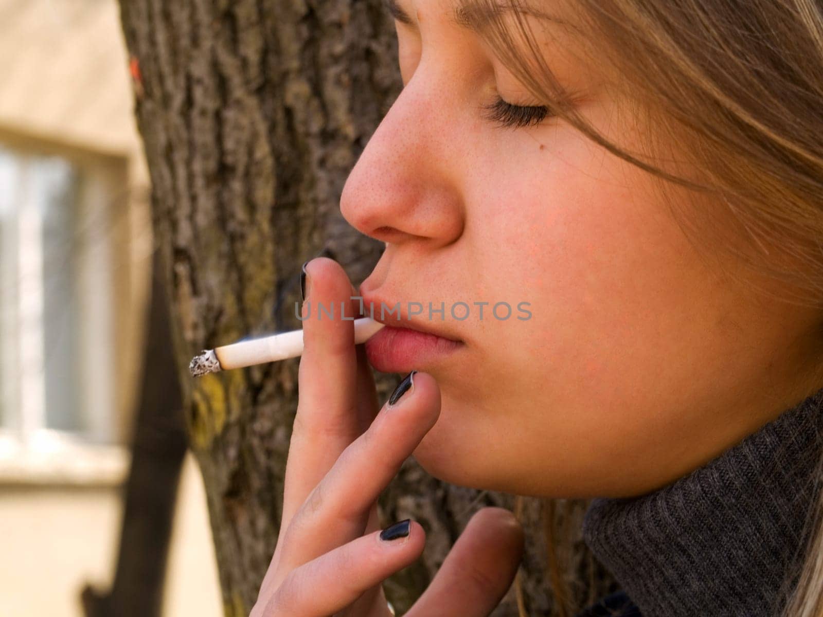 Young student smoking in front of her school