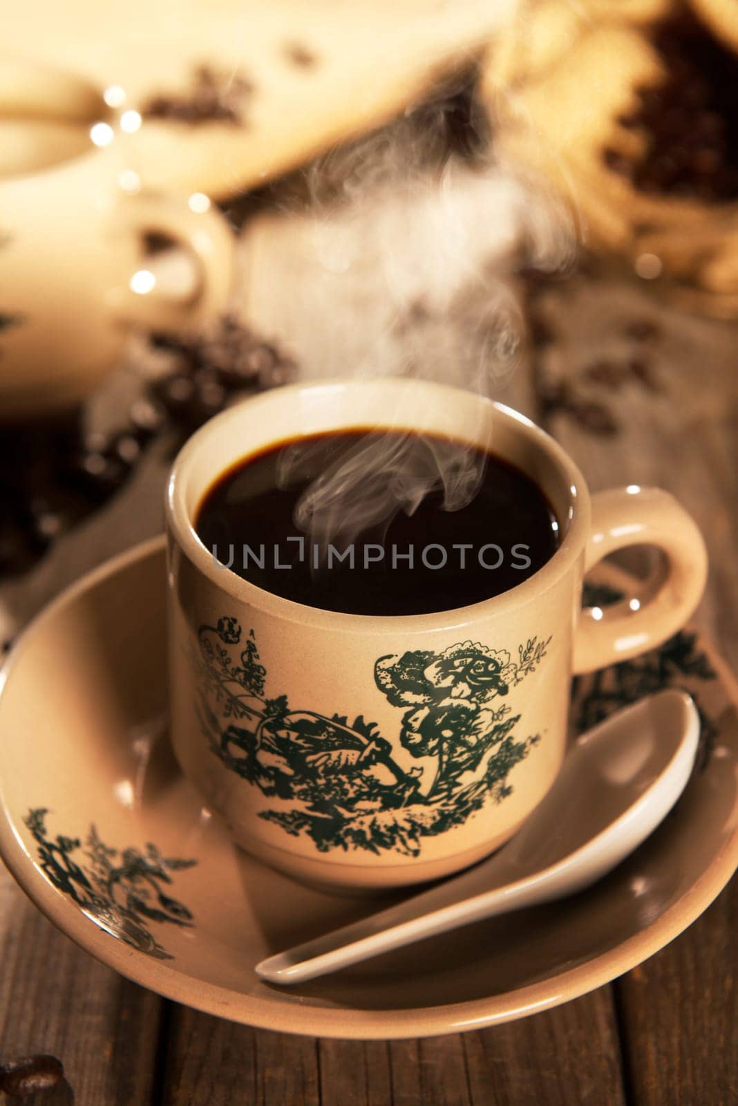 Steaming traditional Chinese nanyang style coffee in vintage mug and saucer with coffee beans. Fractal on the cup is generic print. Soft focus setting with dramatic ambient light on dark wooden background.