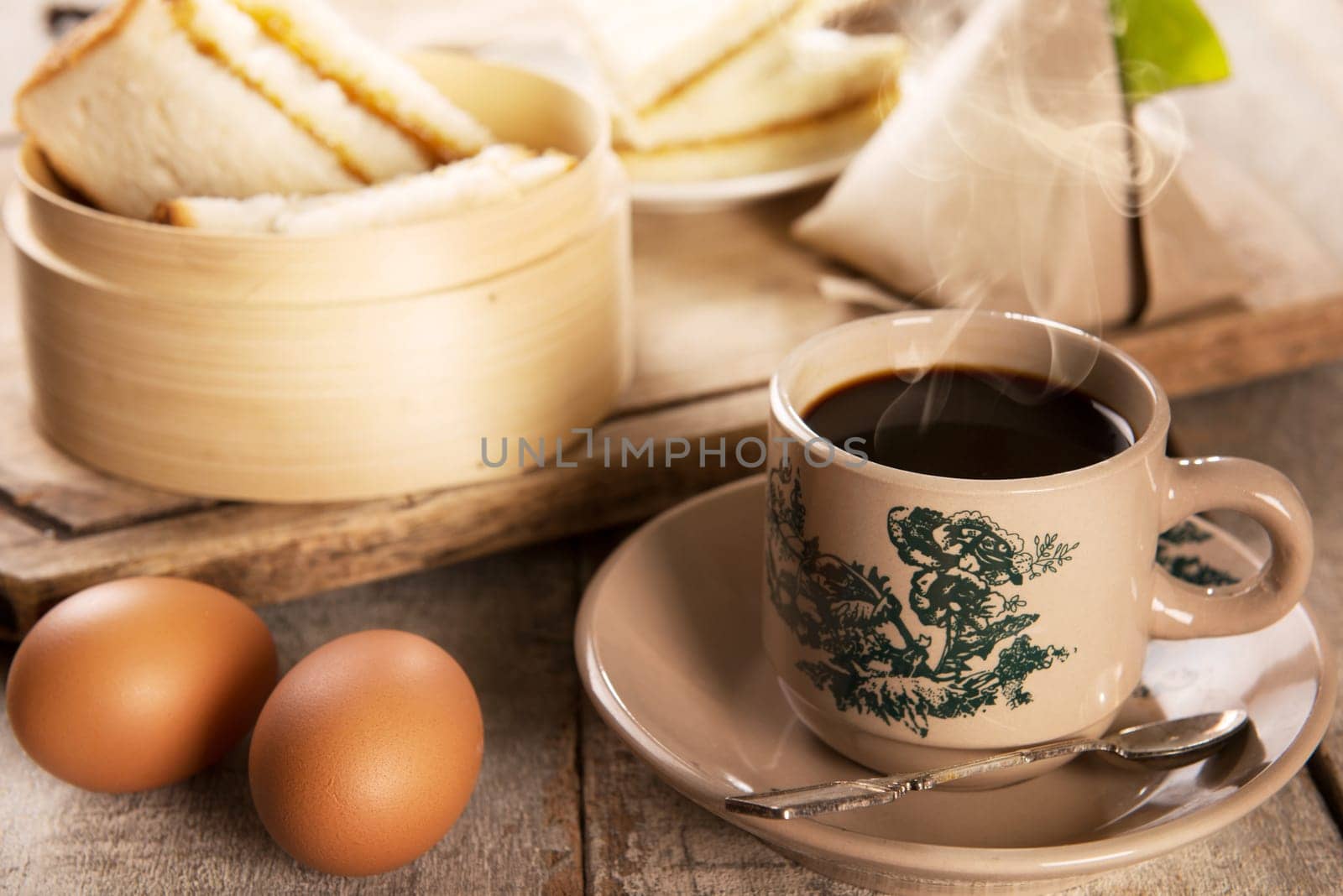 Traditional kopitiam style Malaysian coffee and breakfast. Fractal on the cup is generic print. Soft focus dramatic ambient light over wood table.