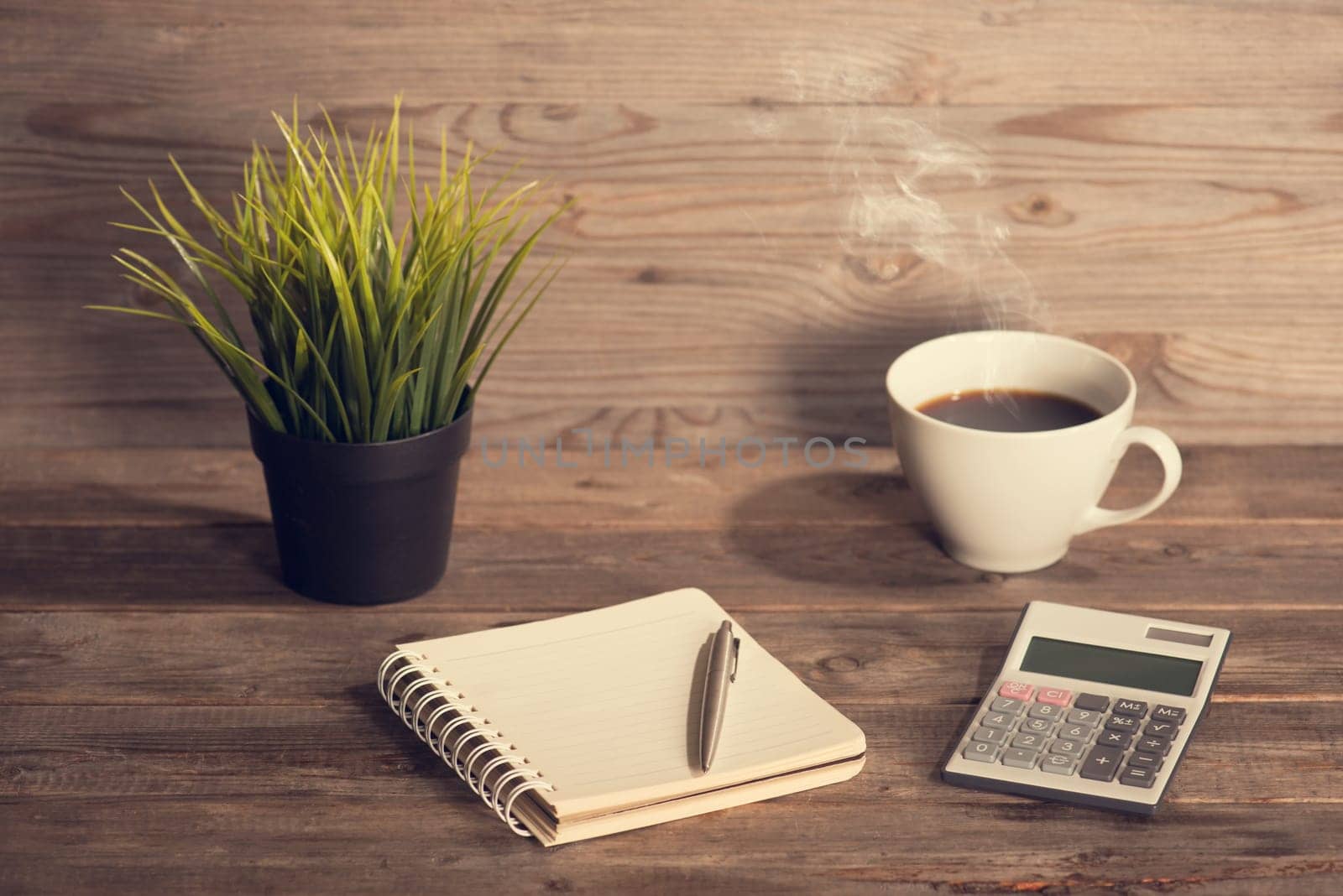 Budget analysis concept. Workplace with booklet, pen, calculator and coffee mug. Wooden table background vintage toned.