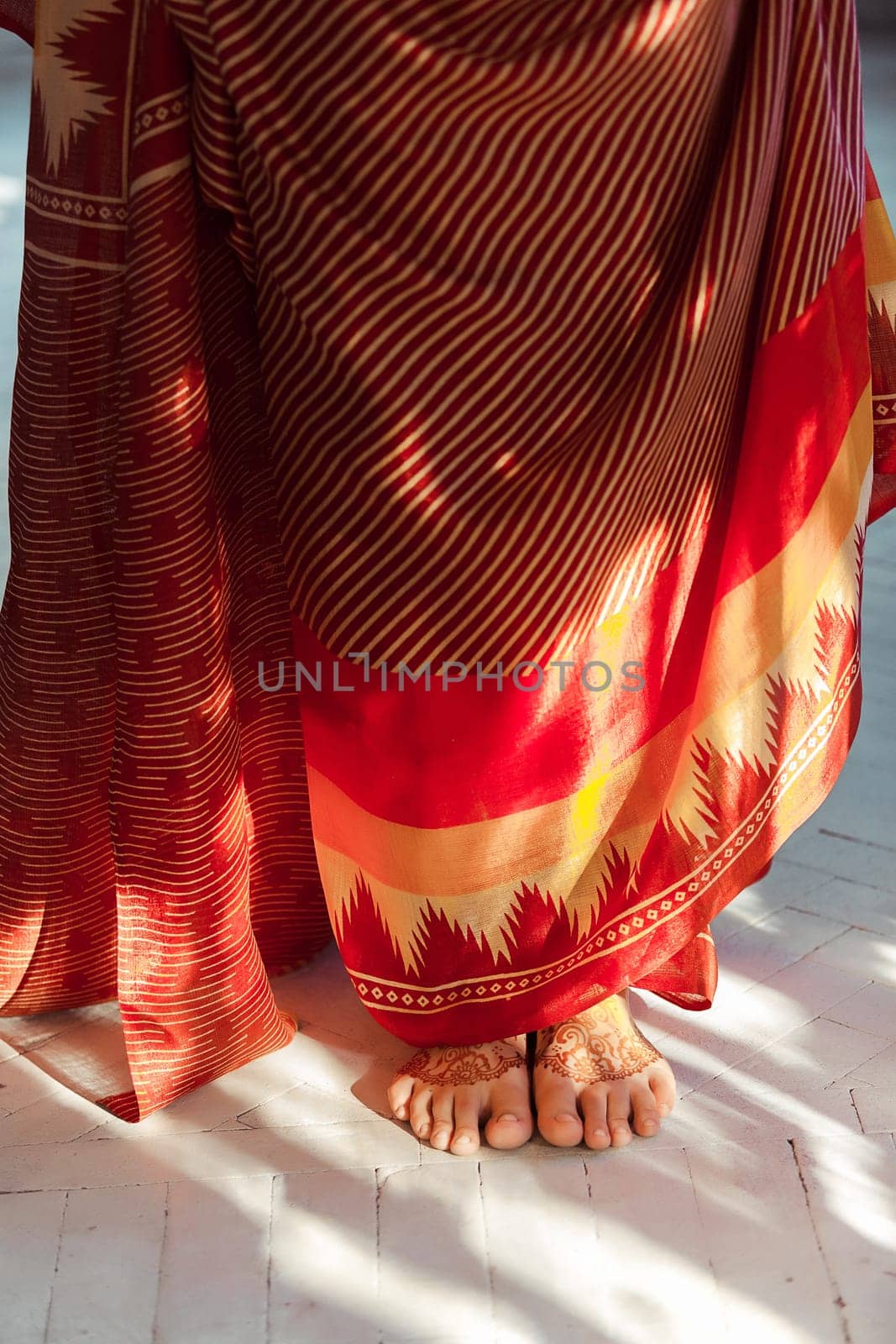 Indian picture on woman feet, mehendi tradition decoration, resistant design by special paint, brown henna.  Indian red dress on white background