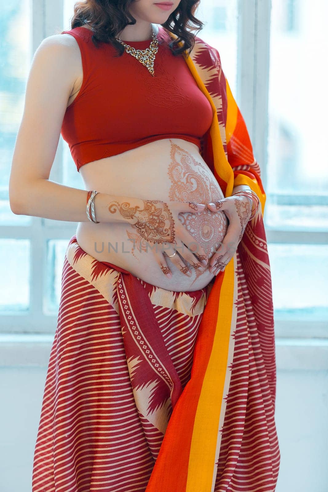 Indian picture on woman hands and pregnant belly with henna tattoo  on white room background