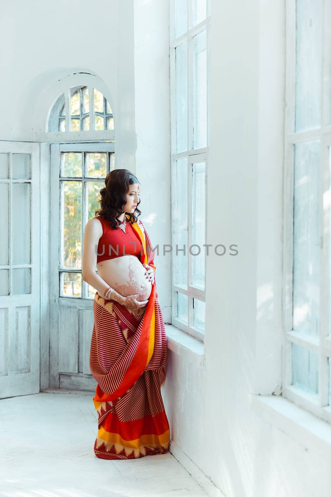 Indian picture on woman hands and pregnant belly with henna tattoo  on white room background