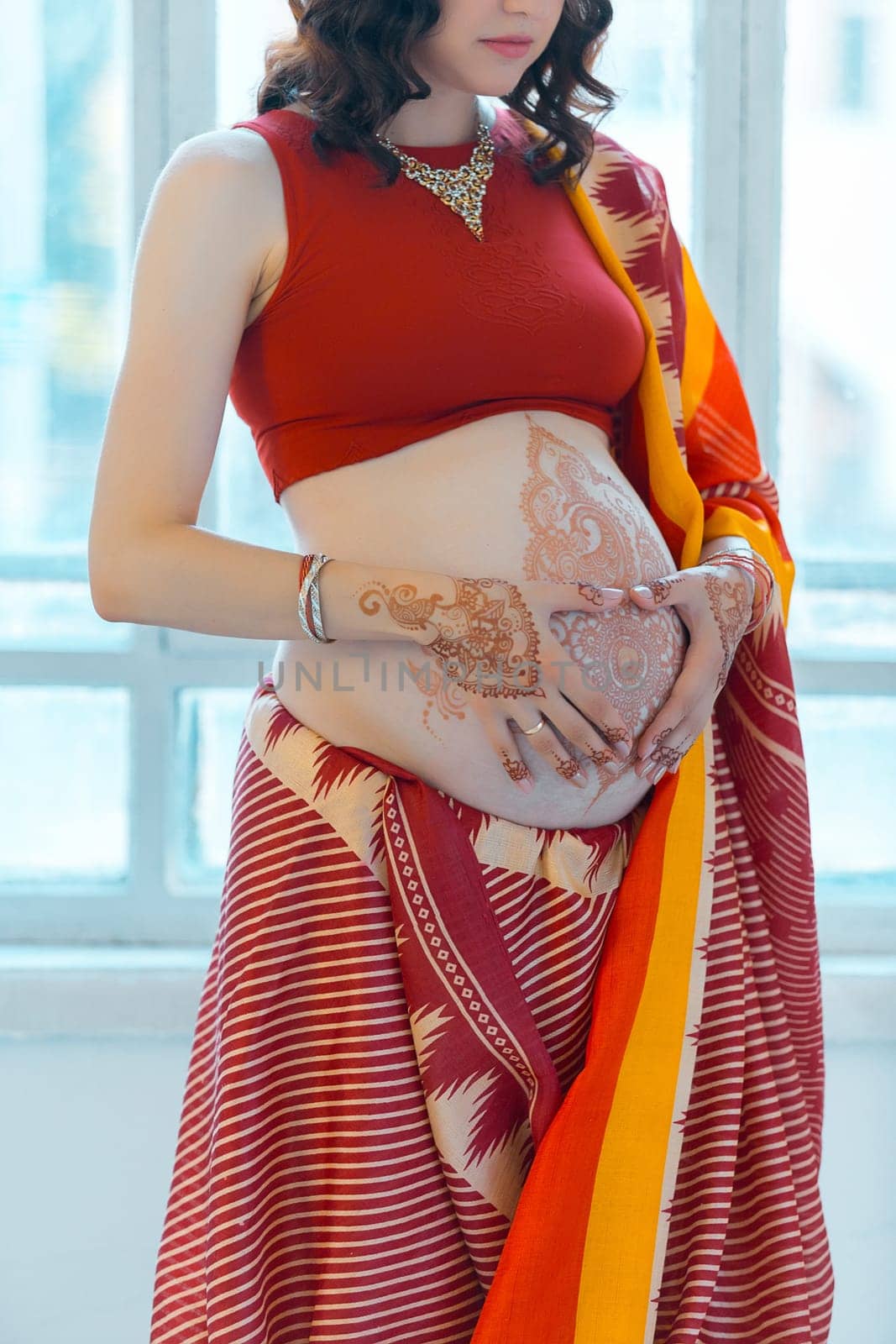 Indian picture on woman hands and pregnant belly with henna tattoo  on white room background