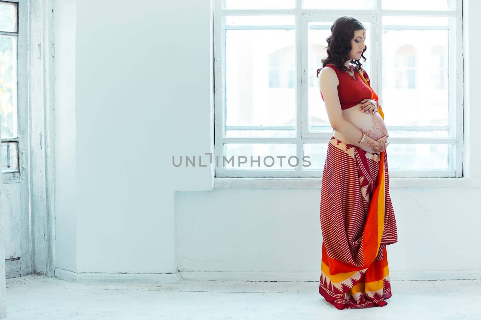 Indian picture on woman hands and pregnant belly with henna tattoo  on white room background