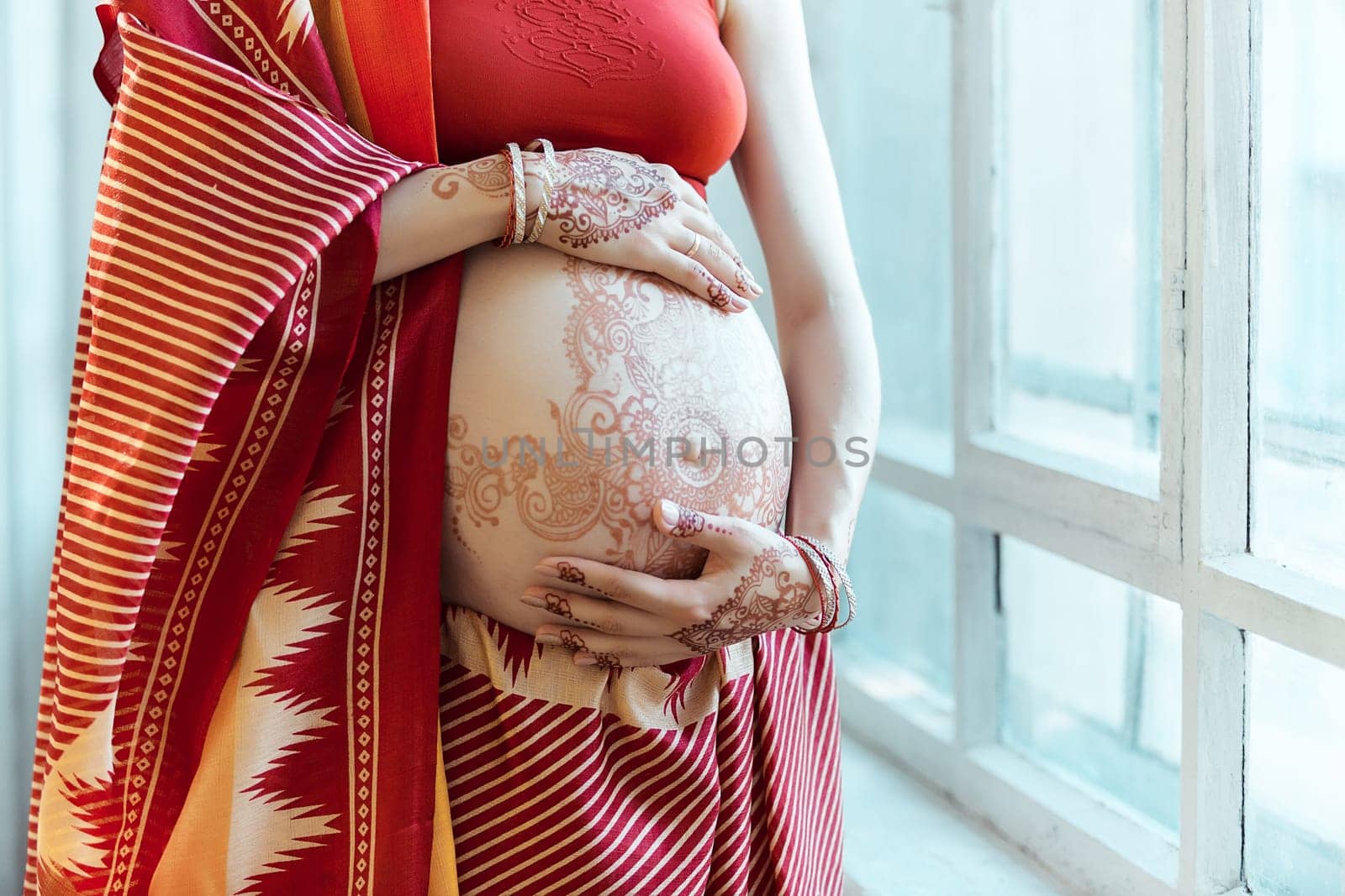 Indian picture on woman hands and pregnant belly with henna tattoo  on white room background