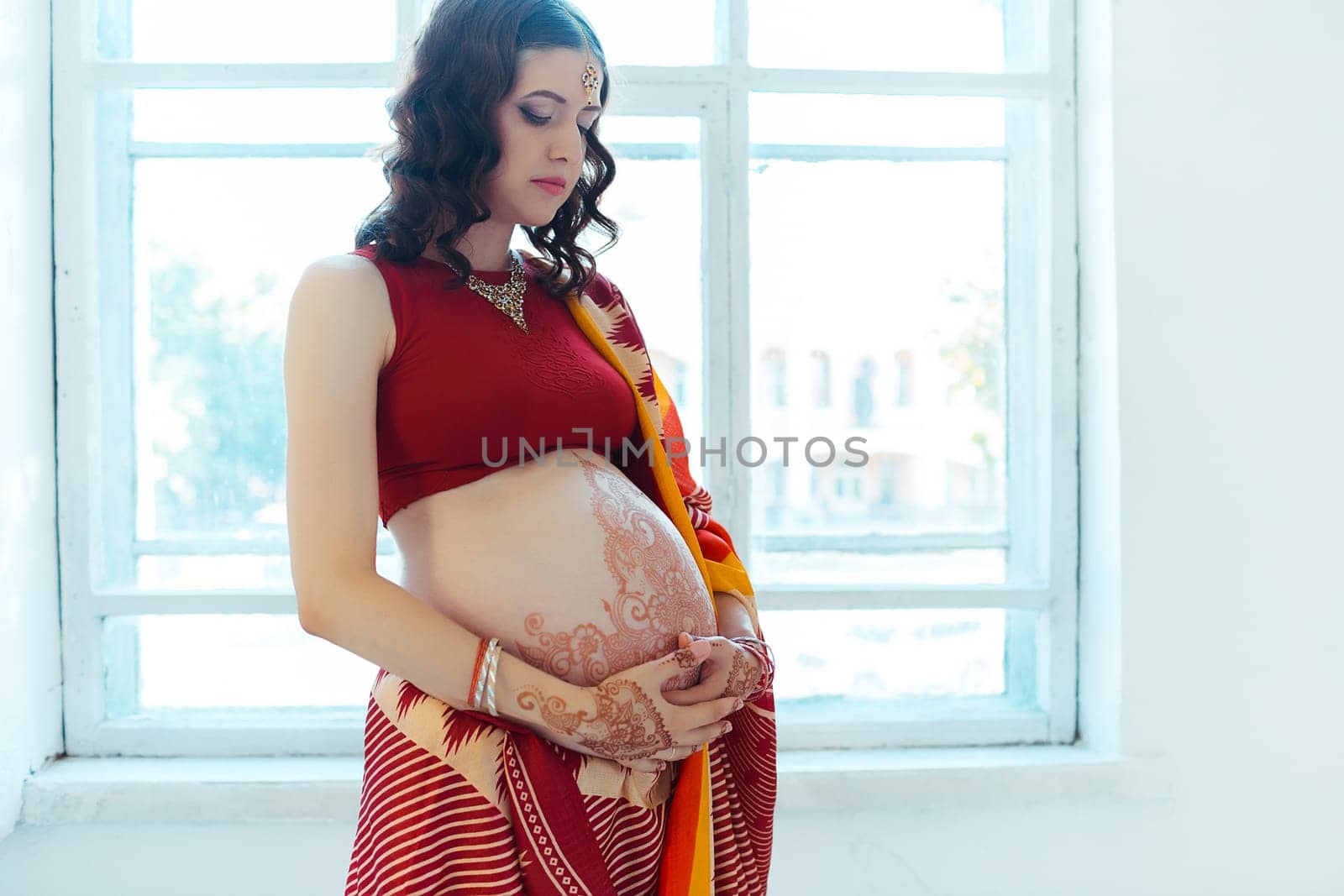 Indian picture on woman hands and pregnant belly with henna tattoo  on white room background