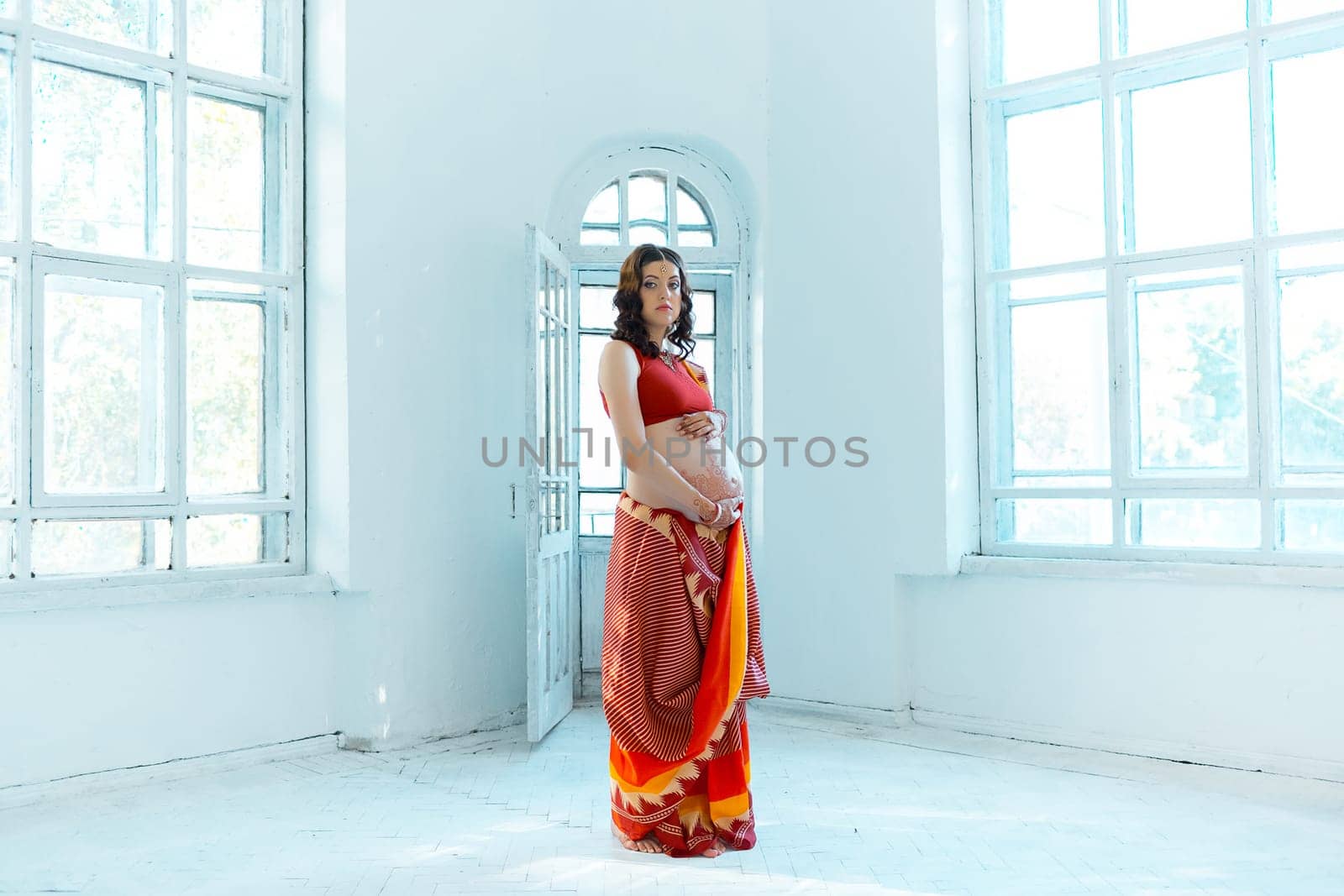 Indian picture on woman hands and pregnant belly with henna tattoo  on white room background