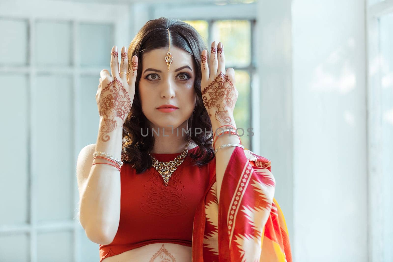 Indian picture on woman hands and belly, mehendi tradition decoration, resistant design by brown henna on white room background