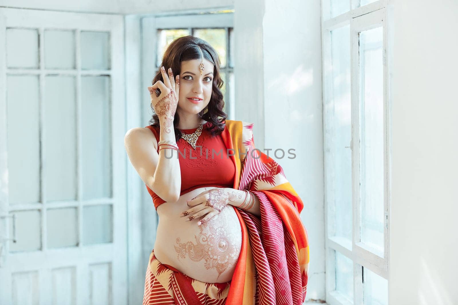 Indian picture on woman hands and pregnant belly with henna tattoo  on white room background