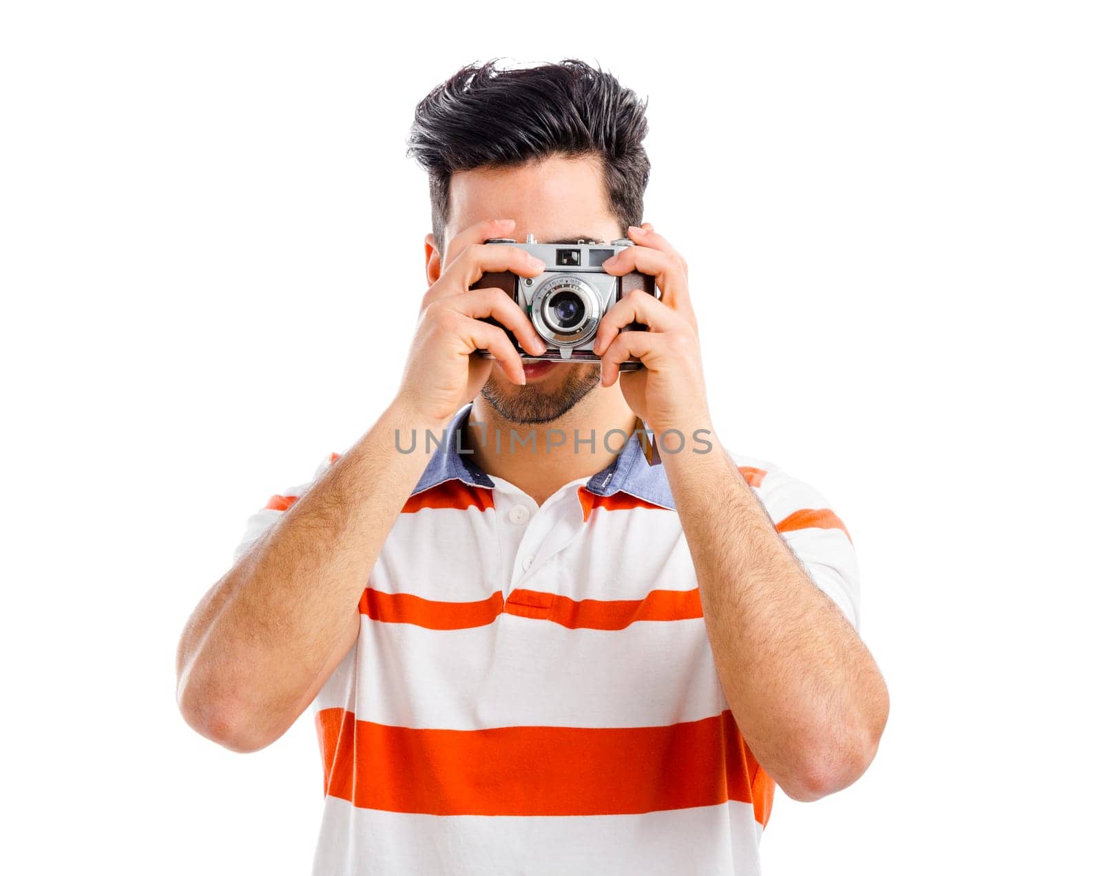 Handsome young man photographing with a vintage camera, isolated over gray background