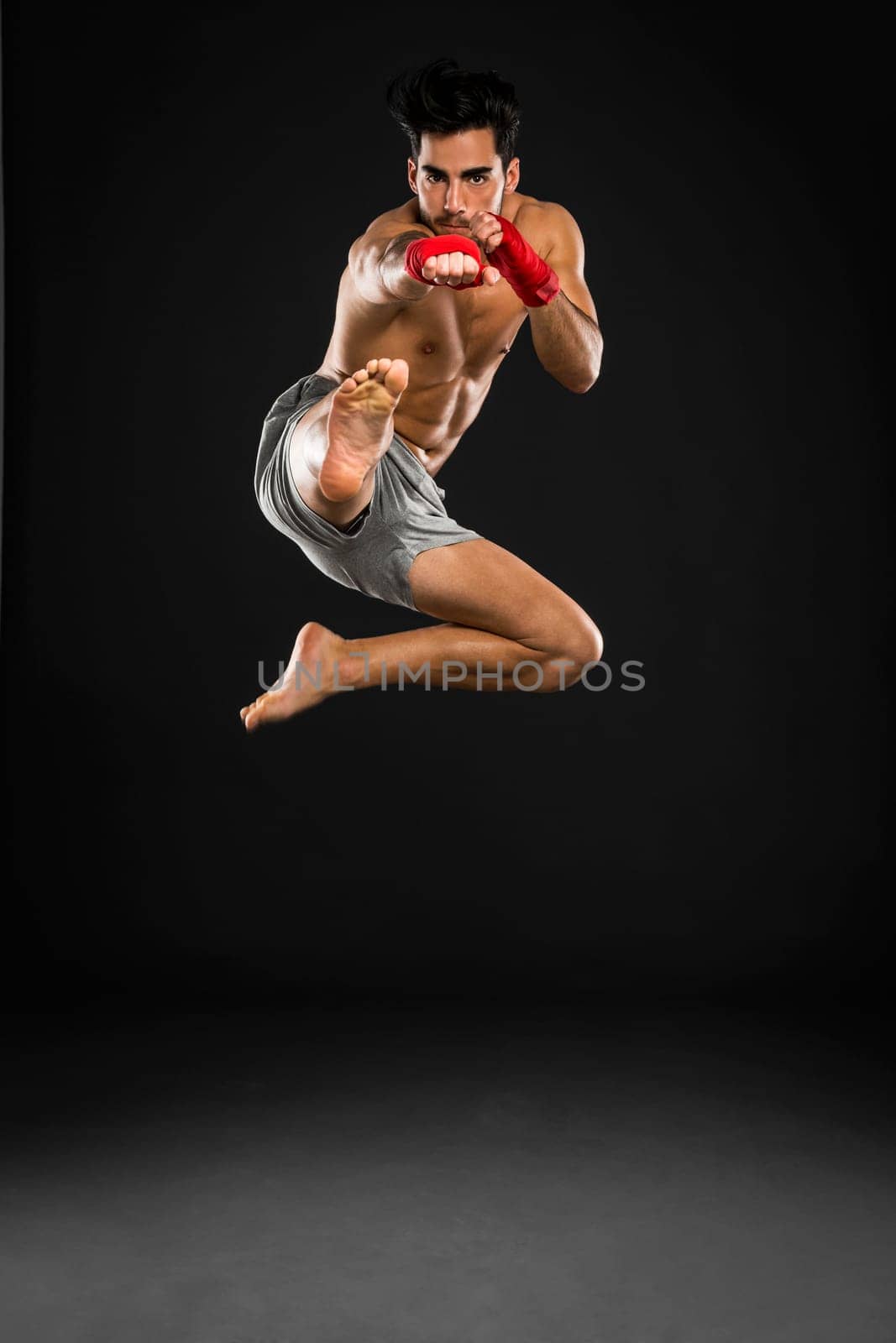 Portrait of a young male Body Combat atlhlete, jumping and kicking