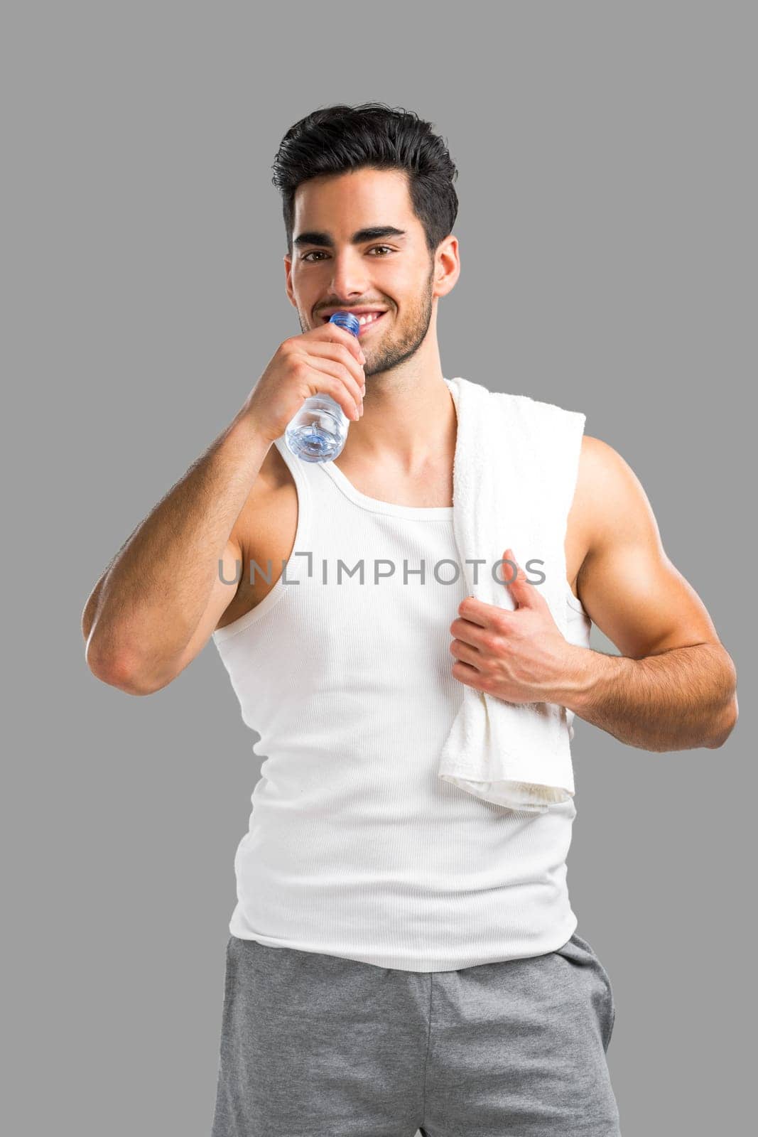 Handsome young man eating a healthy salad, isolated over a gray background
