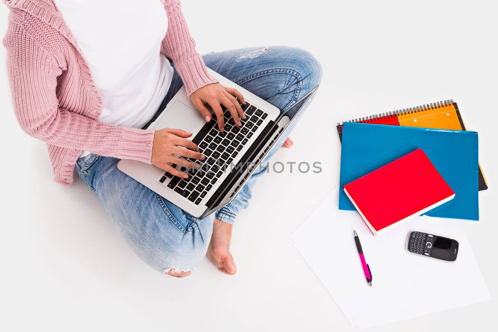 Young female student working with a laptop while drinking coffee, isolated over white background