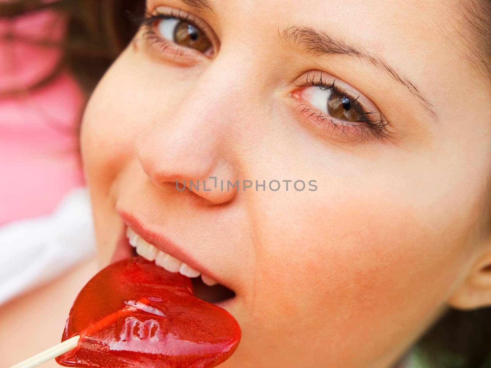 Woman with a heart-shaped lollipop outdoors (&quot Love&quot is written on the lollipop)