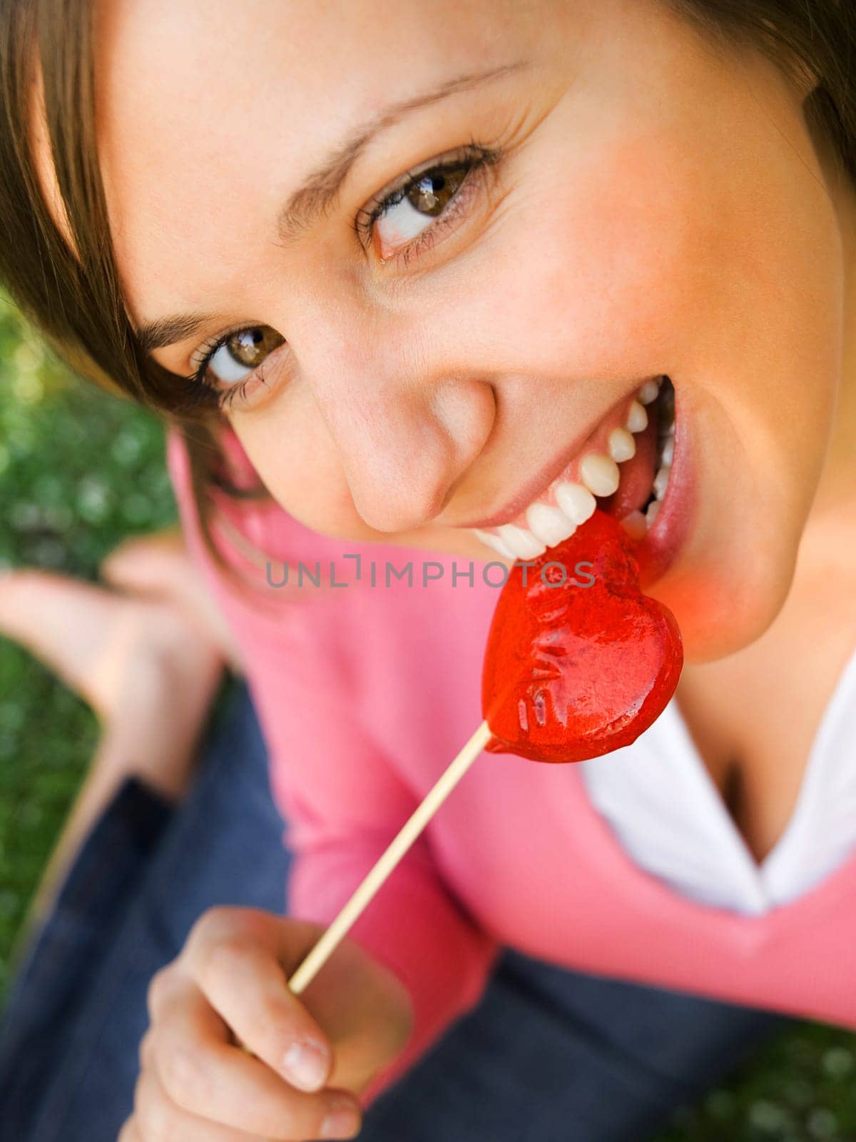 Woman with a heart-shaped lollipop outdoors (&quot Love&quot is written on the lollipop)