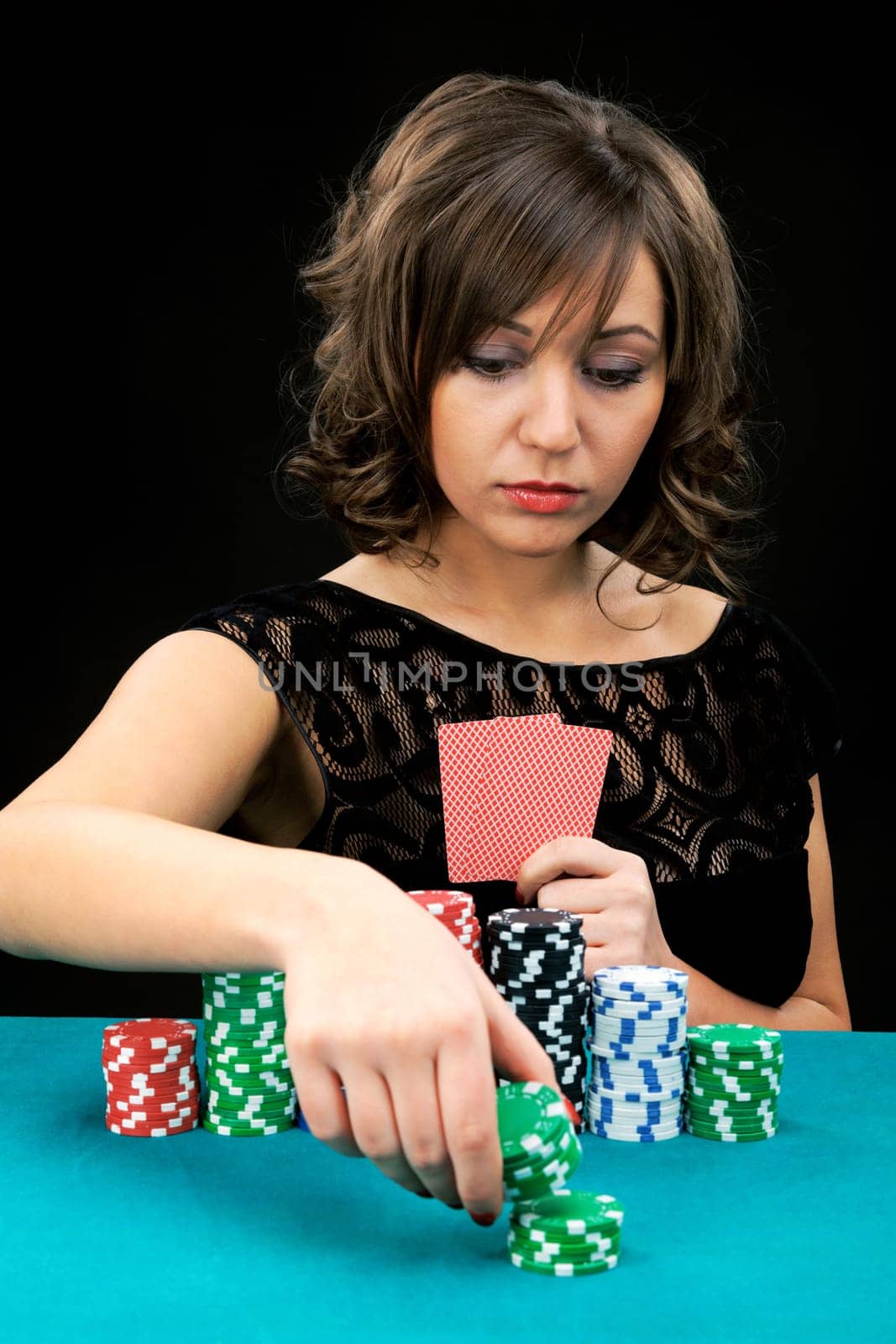 Young woman holding gambling chips on black background