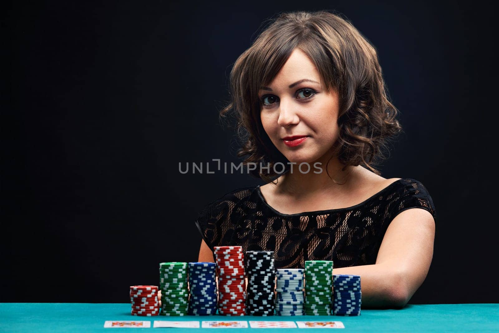 Young woman holding gambling chips on black background