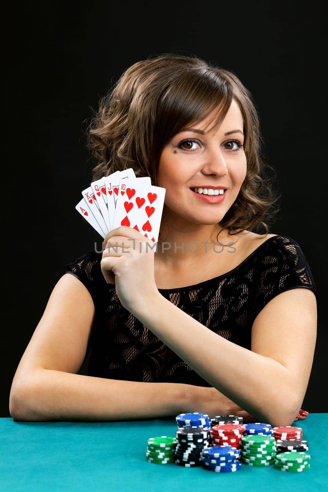Young woman holding gambling chips on black background