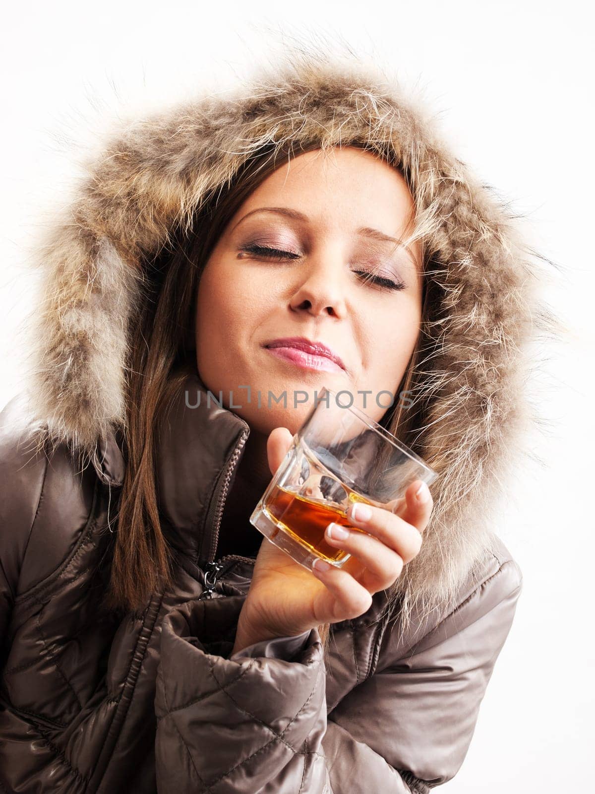 Young woman dressed in winter jacket drinking whiskey