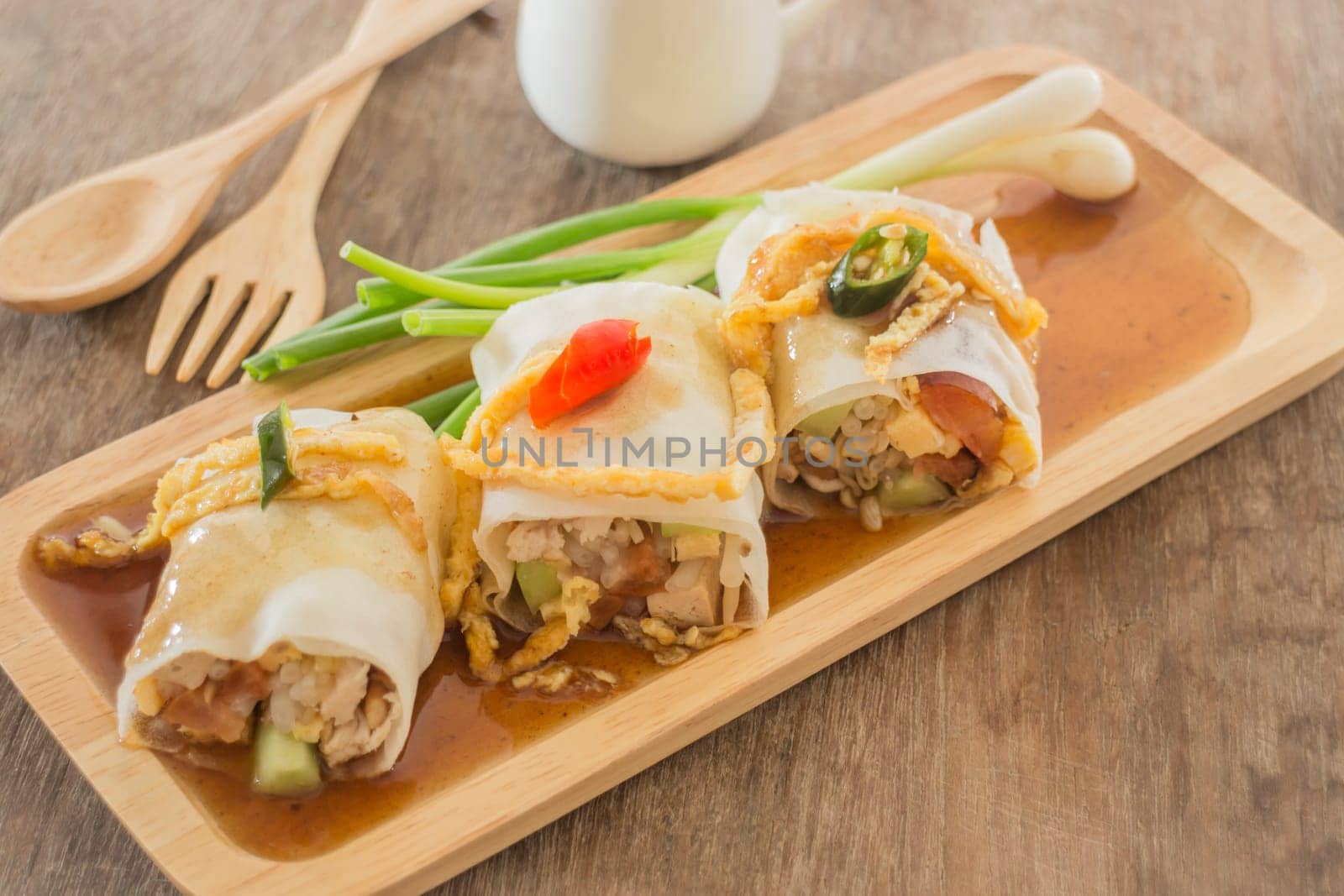 Spring rolls with vegetables and chicken on wooden plate, stock photo