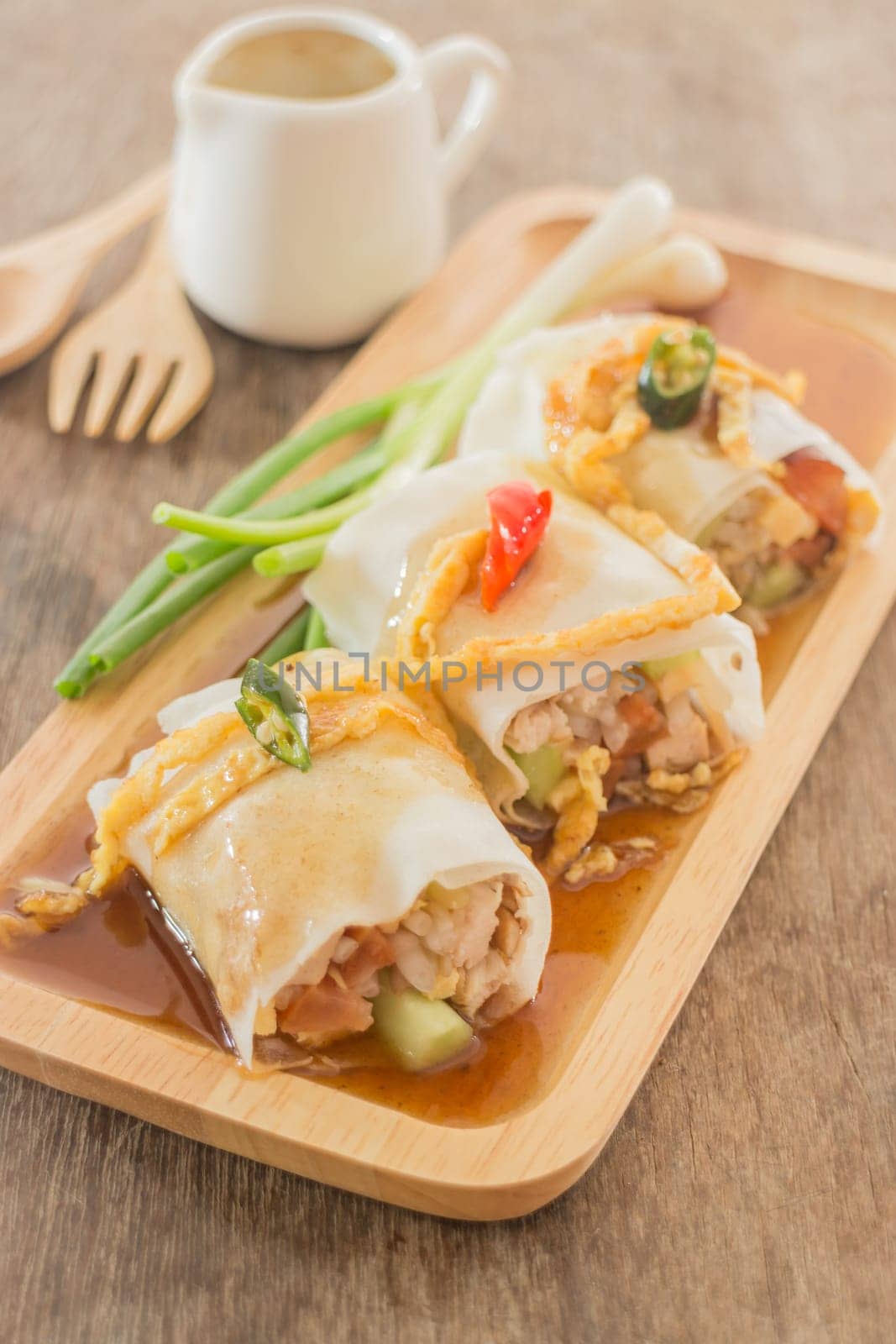 Spring rolls with vegetables and chicken on wooden plate, stock photo