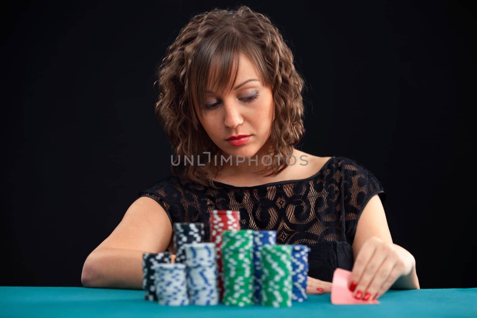 Young woman holding gambling chips on black background