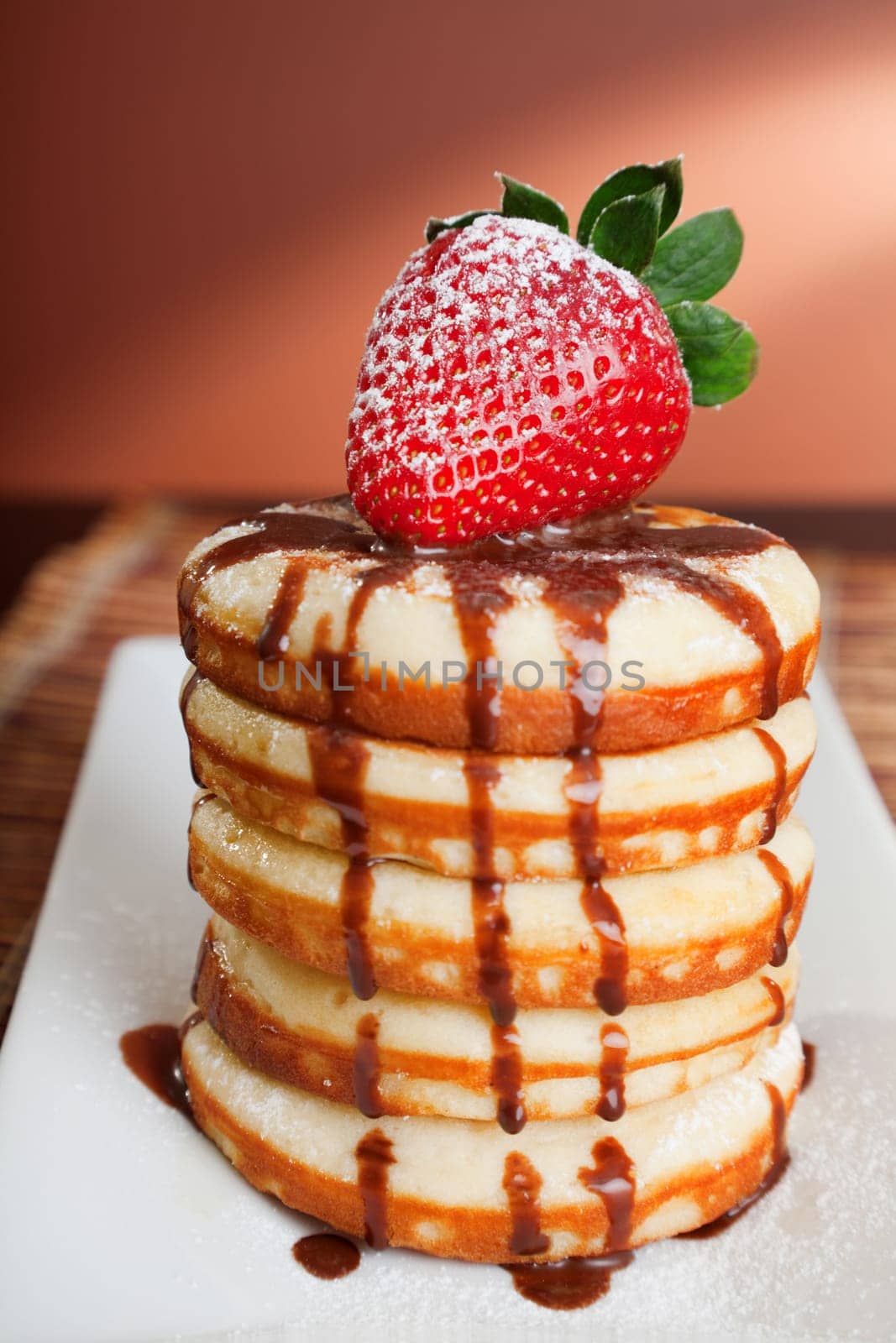 Pancakes with chocolate and strawberries and candies on background