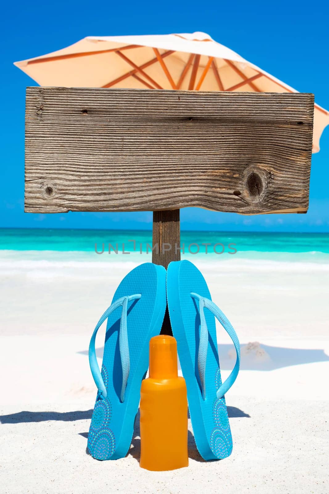 Flips flops stand in front of empty wooden sign on the beach