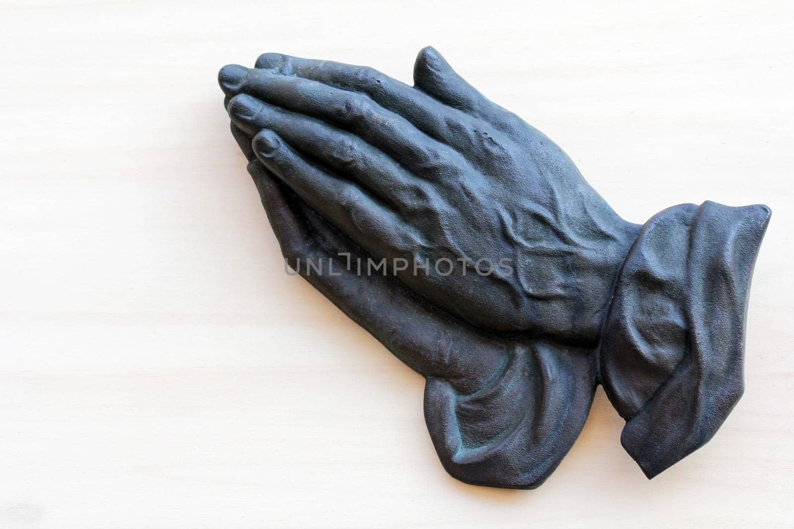 The praying hands of an old woman made of metal