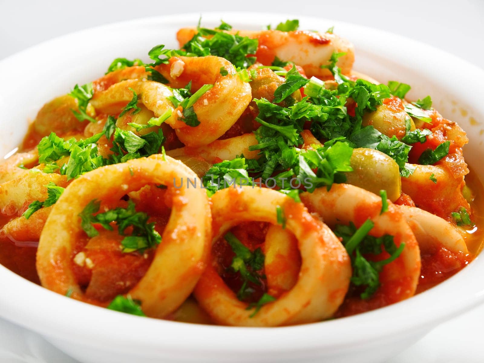 Calamari stewed in tomato and onion souces with olives, topped with parsley
