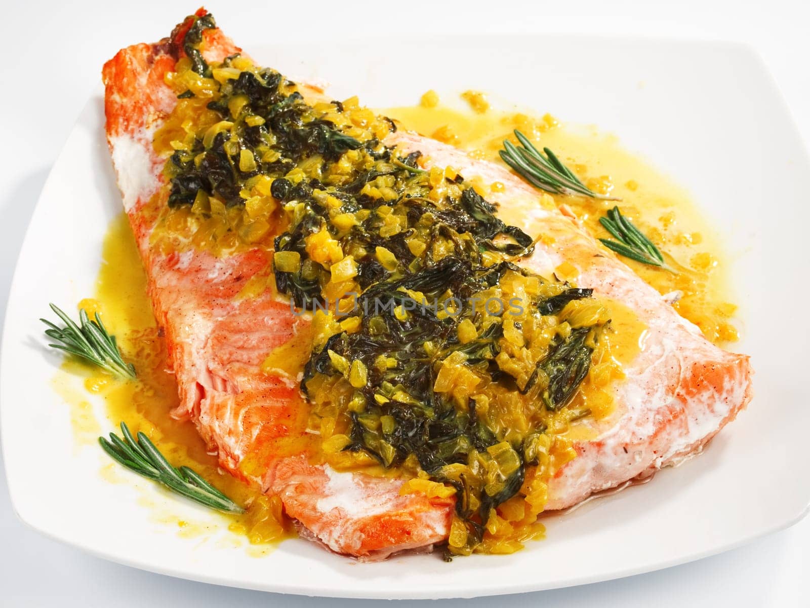Salmon with sauce of saffron, onion and rosemary served in white plate