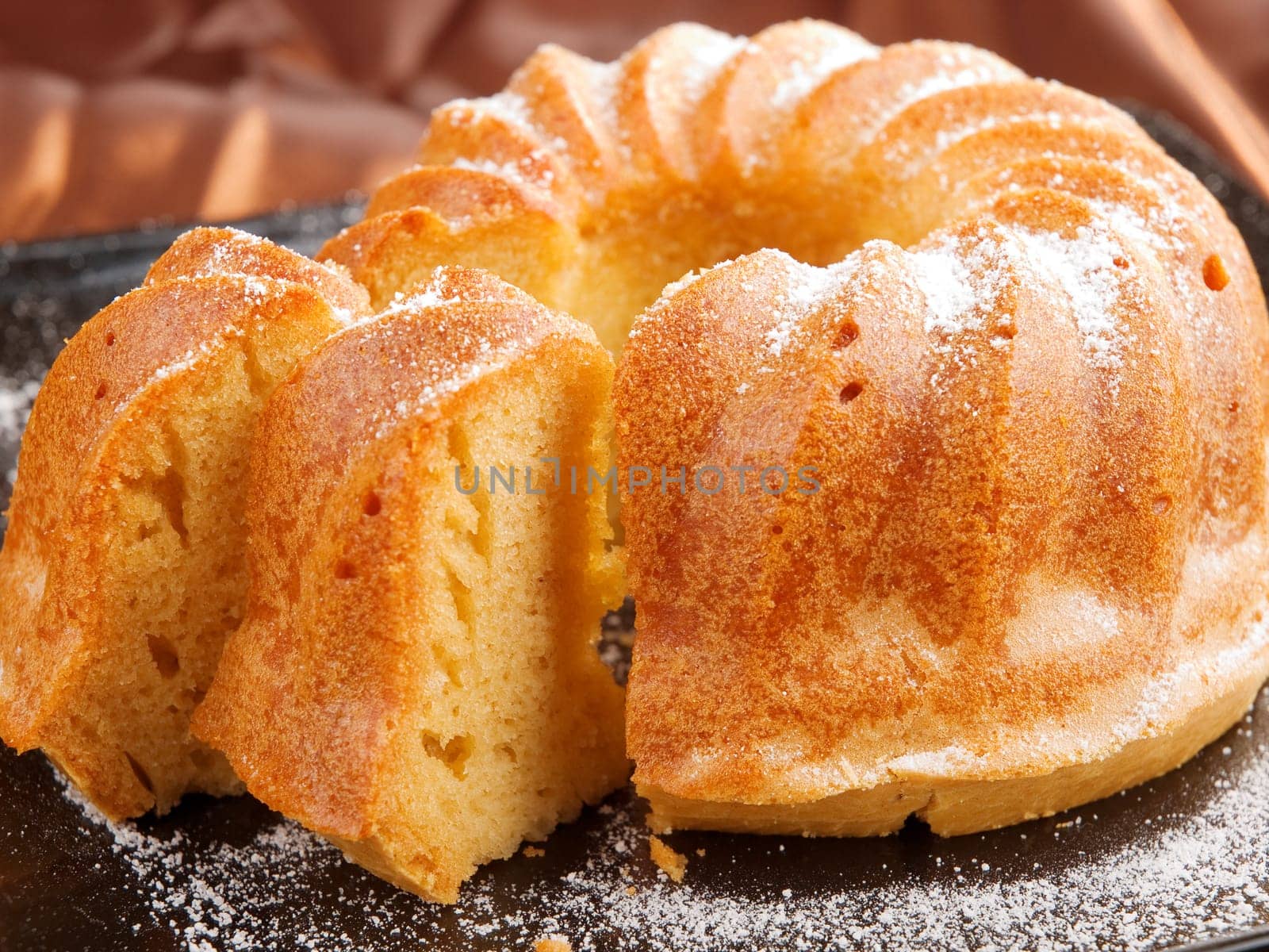 Vanilla cake with one piece of it on brown background
