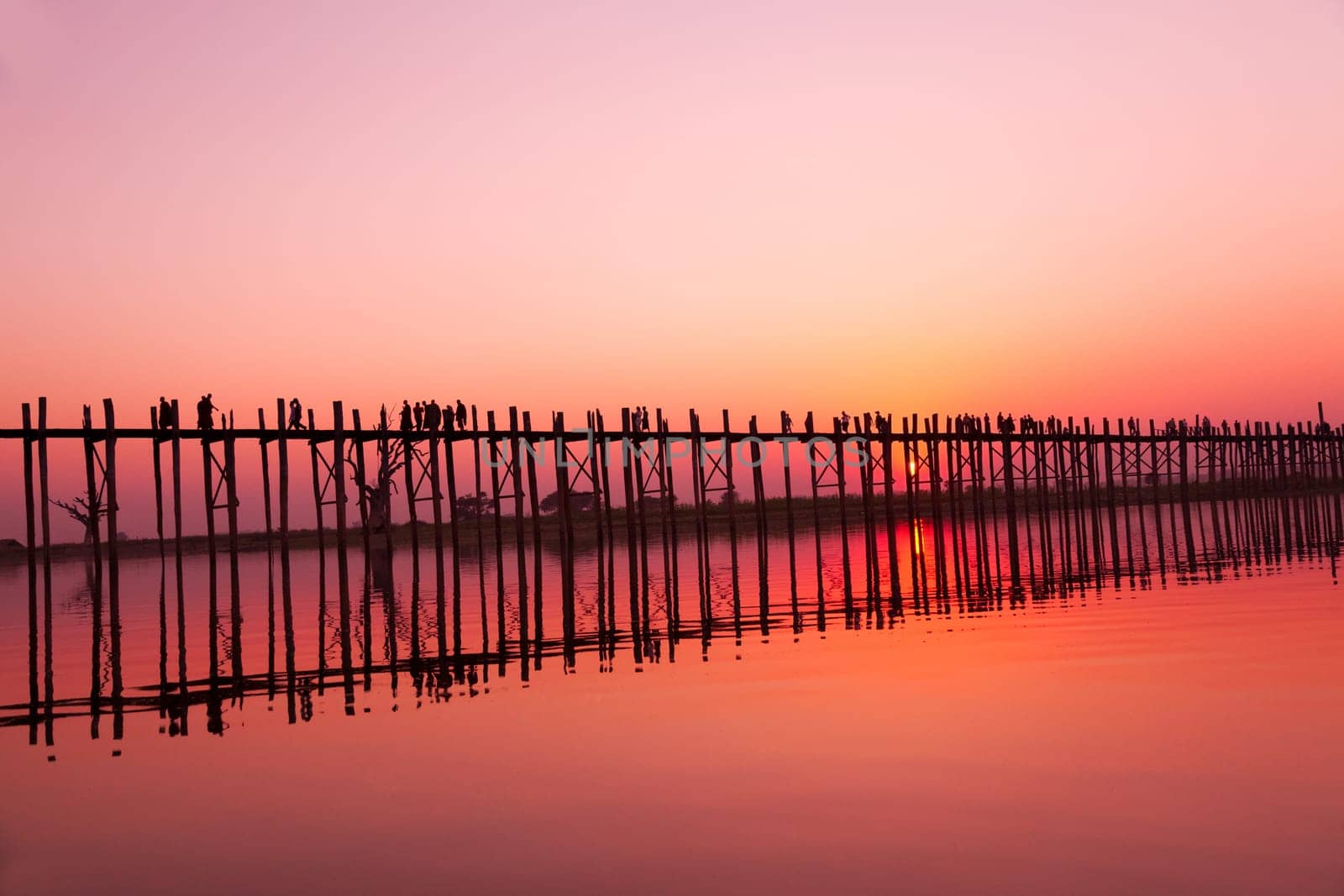 U Bein Bridge at sunset with people crossing Ayeyarwady River, Mandalay, Myanmar