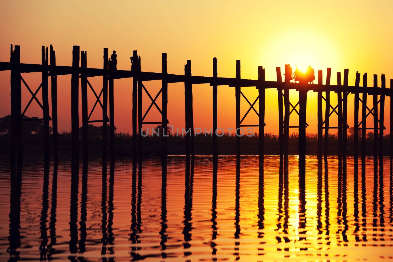U Bein Bridge at sunset with people crossing Ayeyarwady River, Mandalay, Myanmar