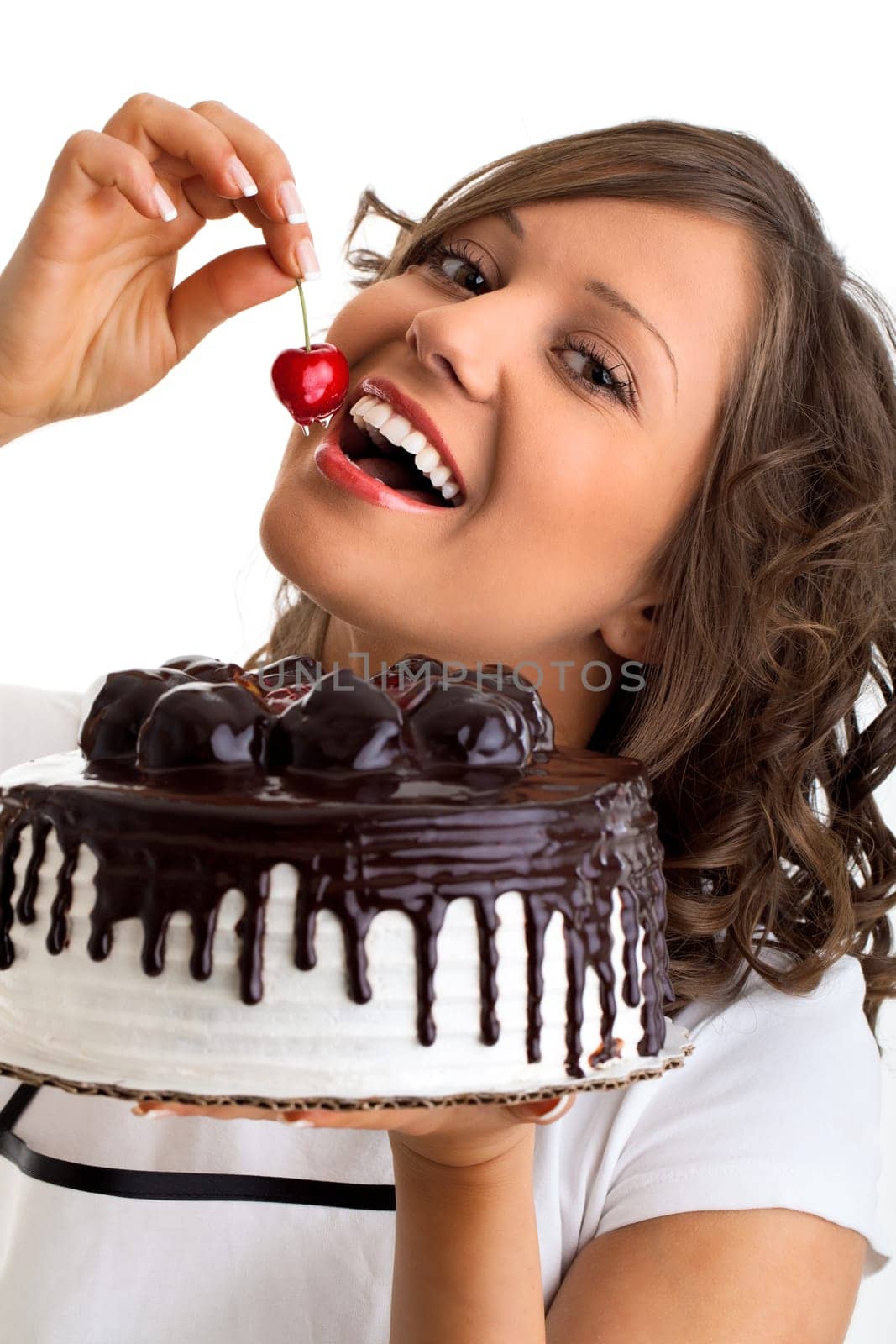 Young woman eating cherry from a chocolate cake, isolated on white