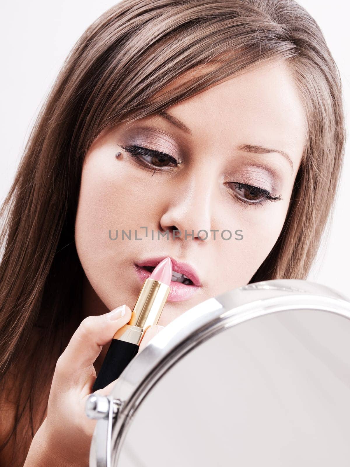 Applying make-up on young woman face, reflection in the mirror