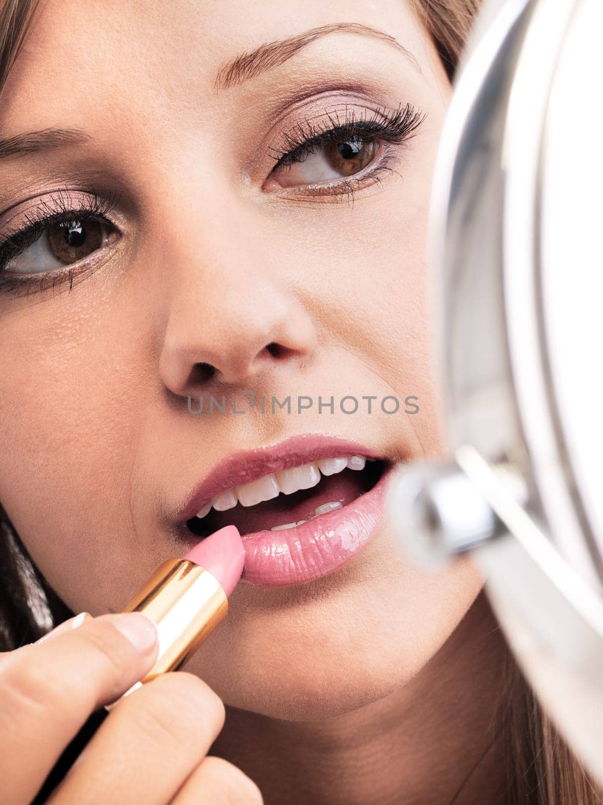 Applying make-up on young woman face, reflection in the mirror
