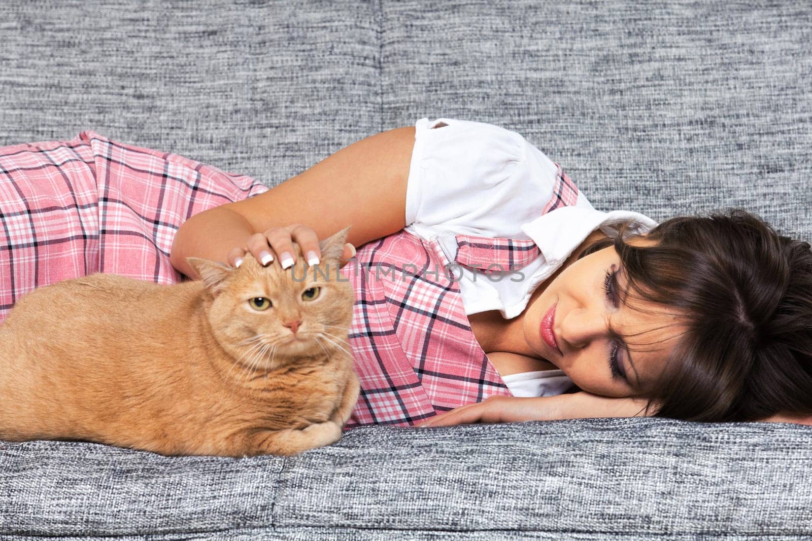Young woman with cat lying on the sofa