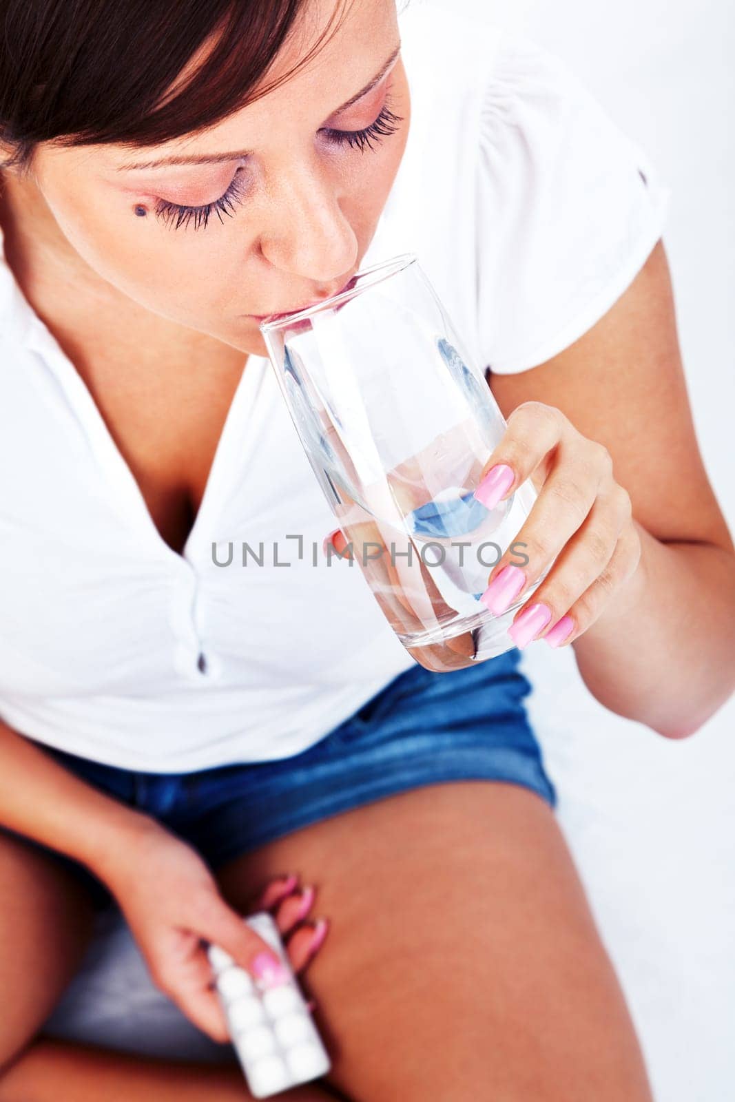 Young woman taking a pill isolated on white background