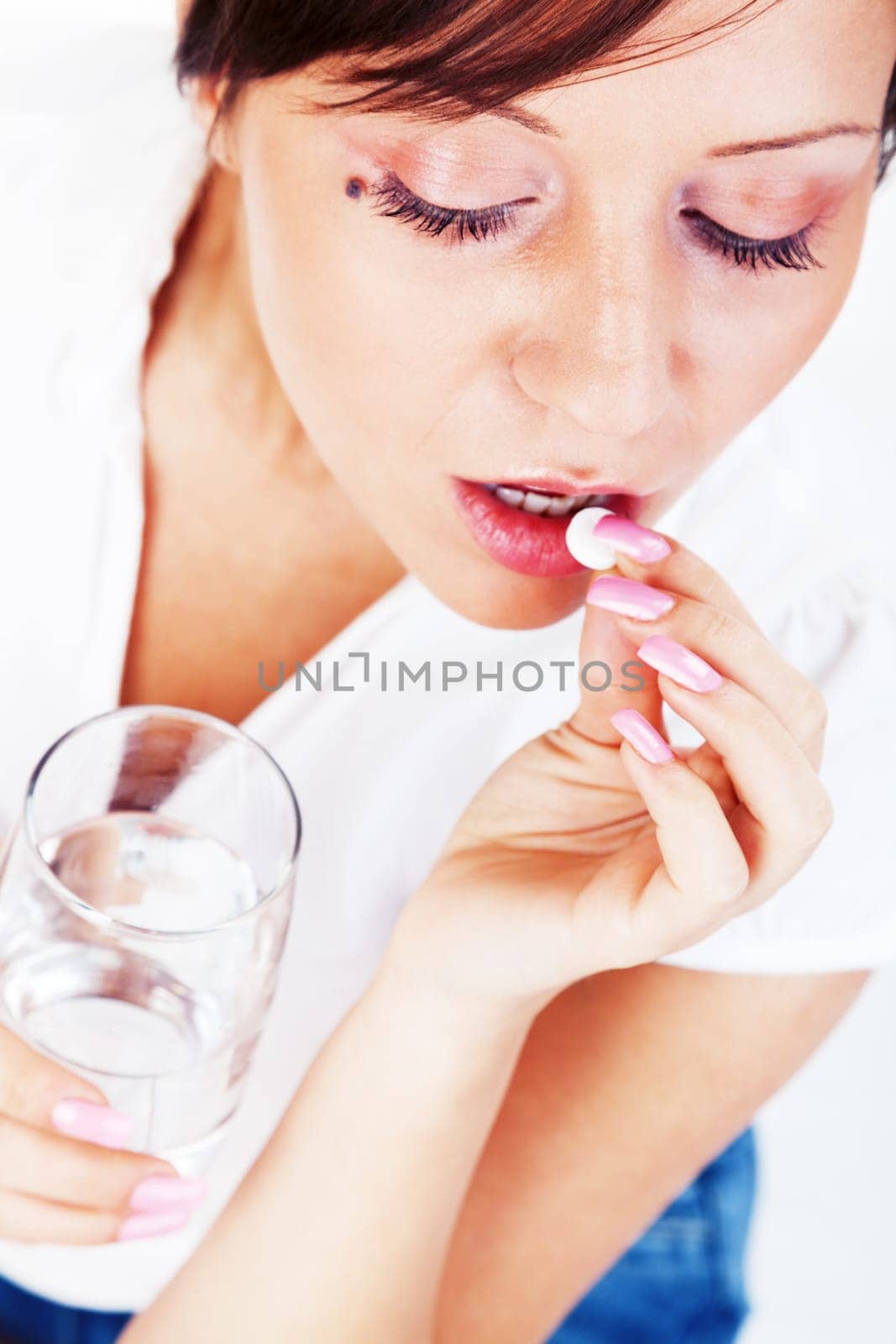 Young woman taking a pill isolated on white background