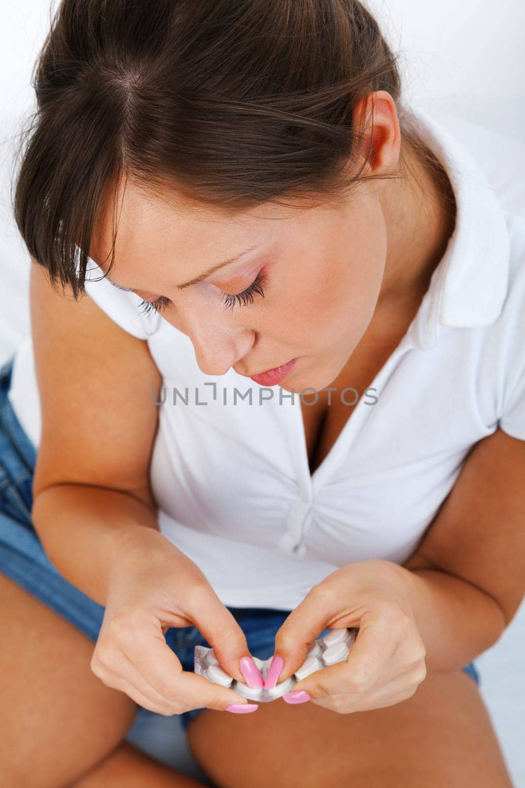Young woman taking a pill isolated on white background