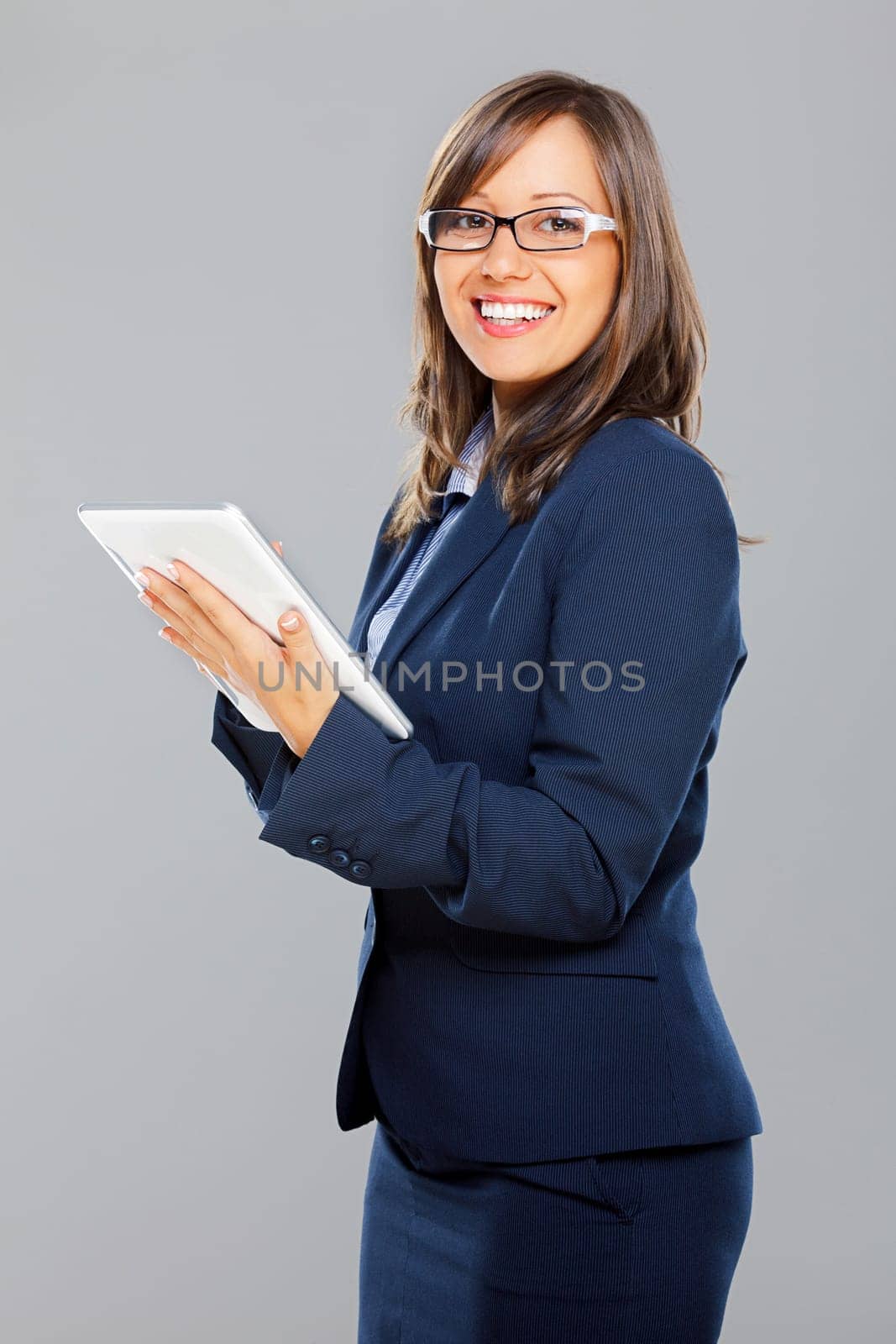 Businesswoman holding tablet isolated on gray background smiling