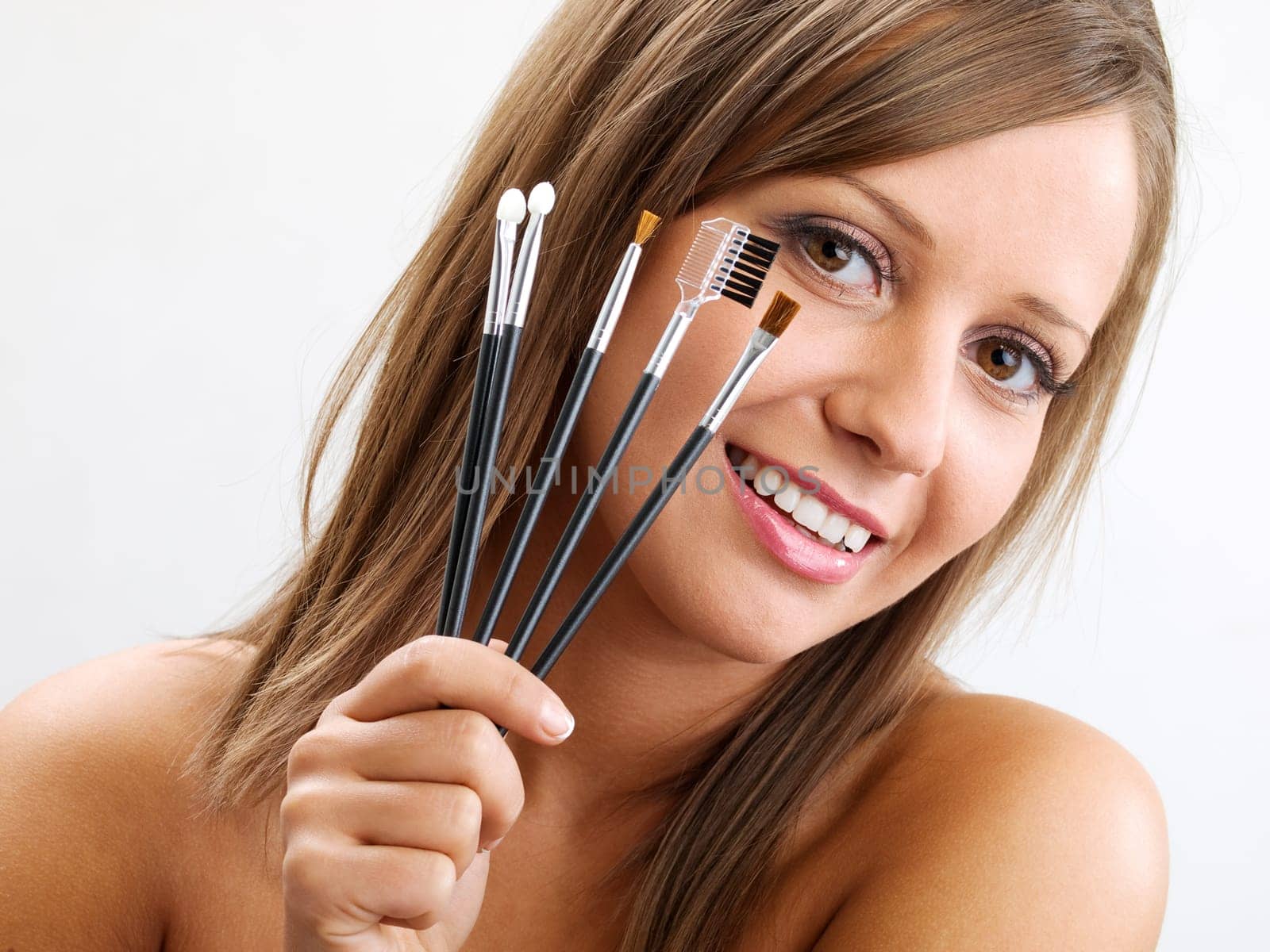Close up of young woman face, holding all types of brushed in one hand