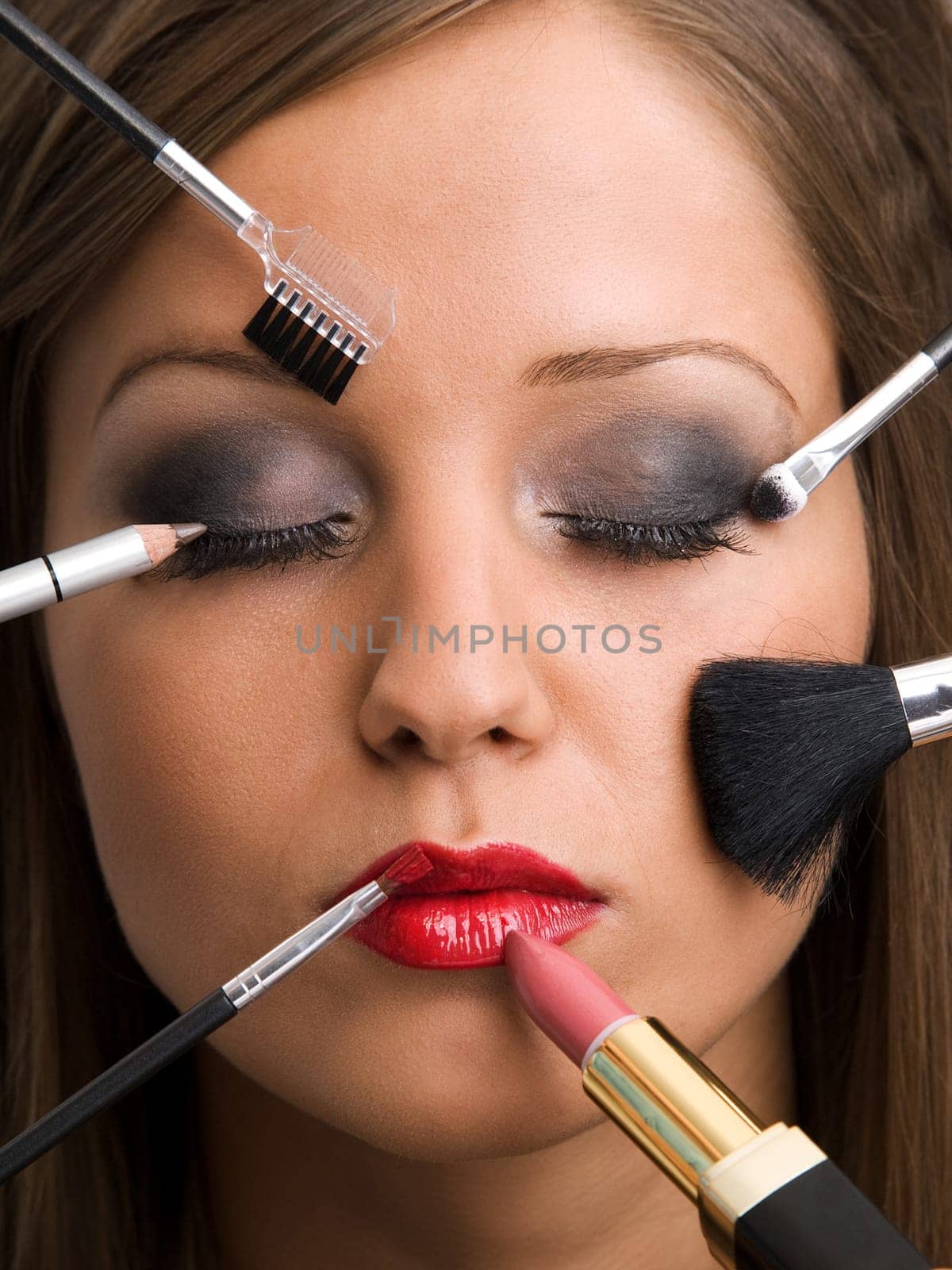 Close up of young woman face with all kinds of make up tools - brush, lipstick etc.