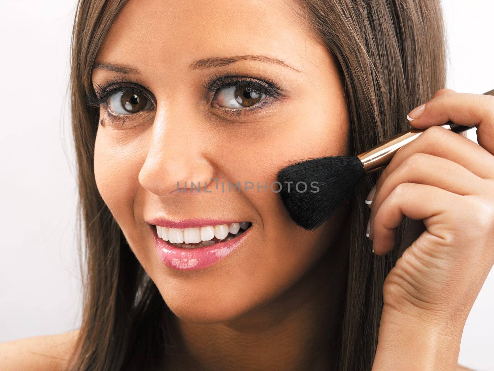 Close up of young woman face, holding a make up brush in one hand