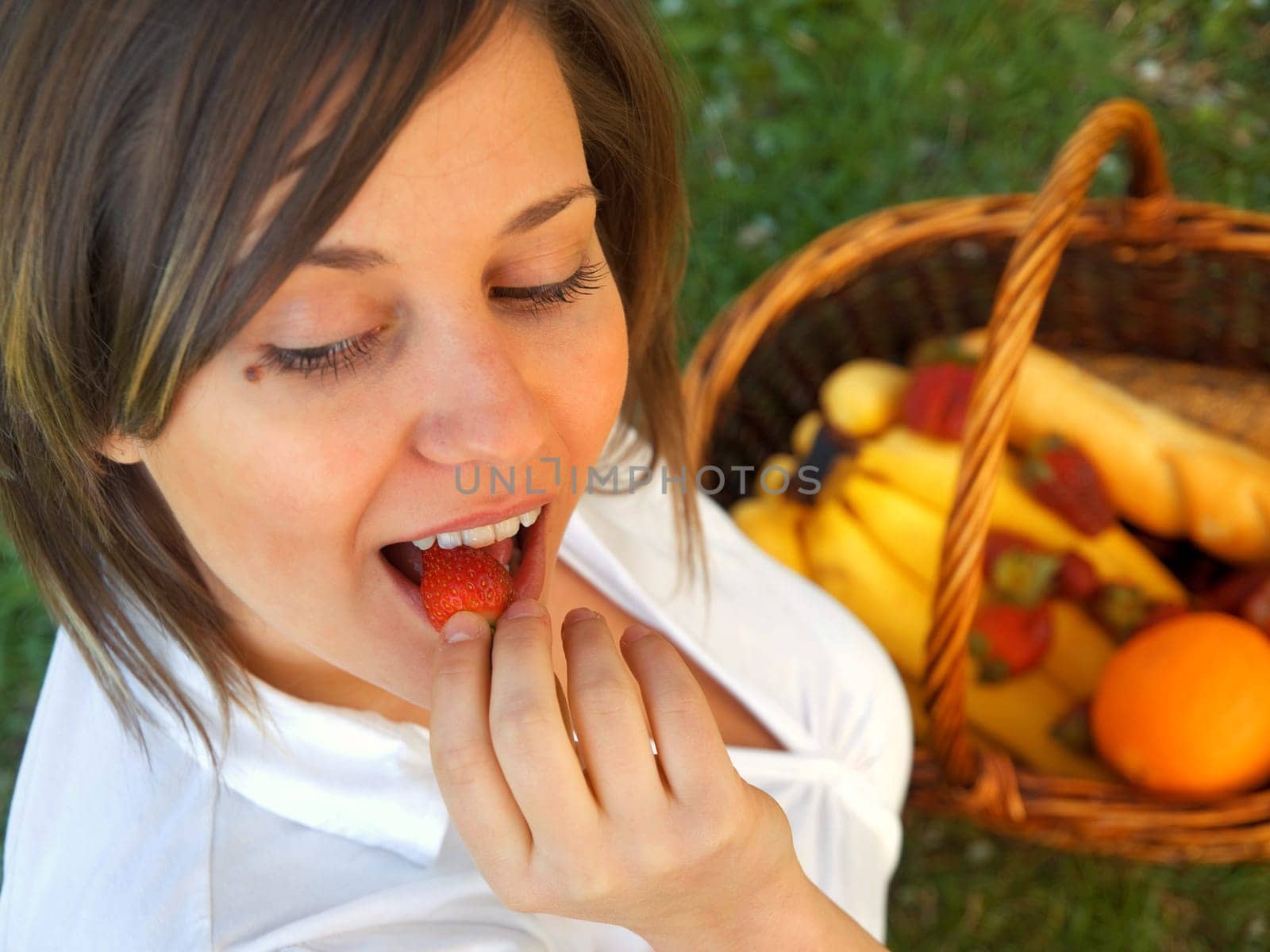Young woman eating strawberry outdoors