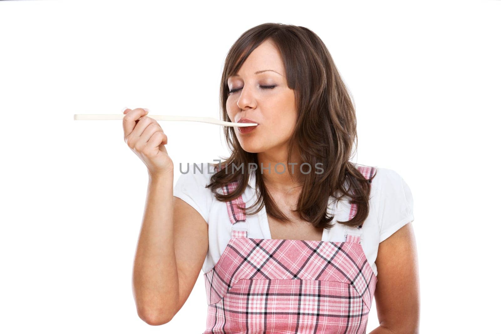 Young woman tasting sauce with a wooden spoon, isolated on white background