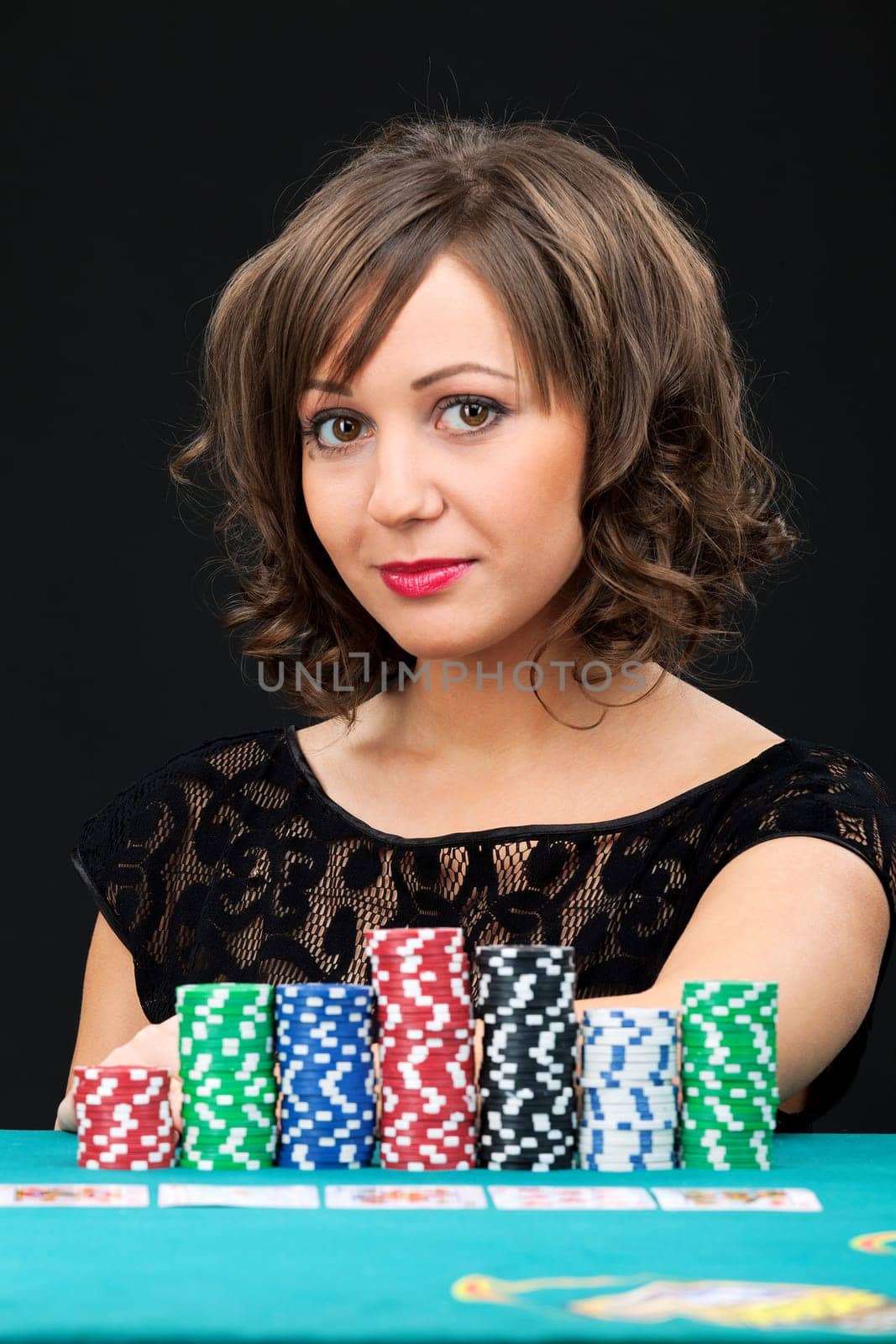 Young woman holding gambling chips on black background