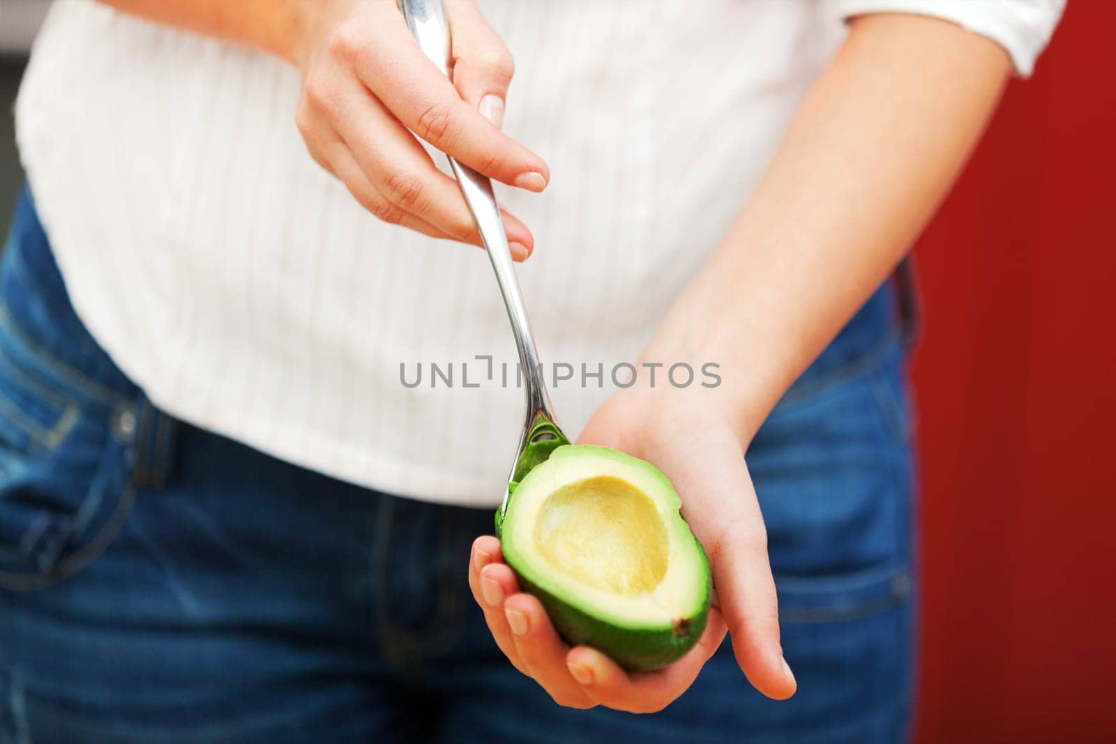 Young woman making salad in the kitchen - peeling avocado